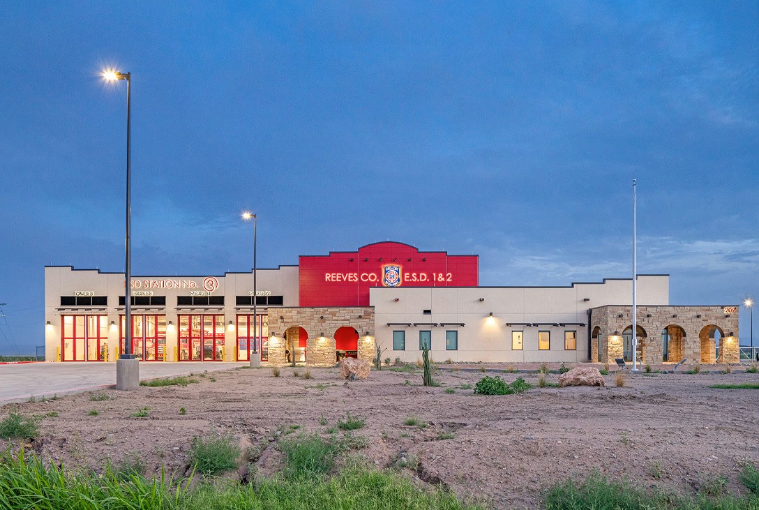 Front elevation at dusk with illuminated department signage at Reeves County ESD 1 & 2 Fire Station 3, by Martinez Architects