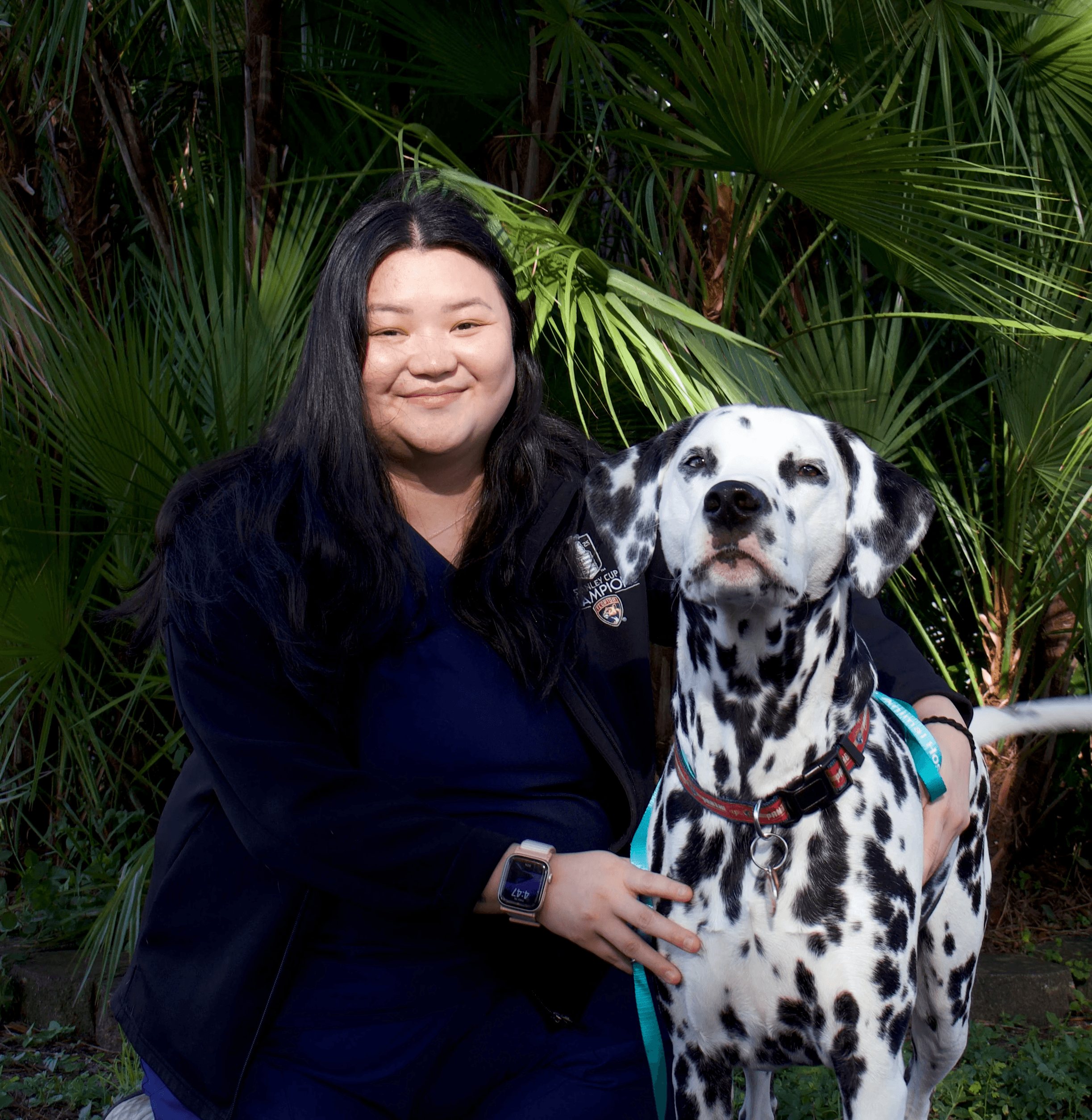 dominique kneeling next to a dalmation in front of greenery