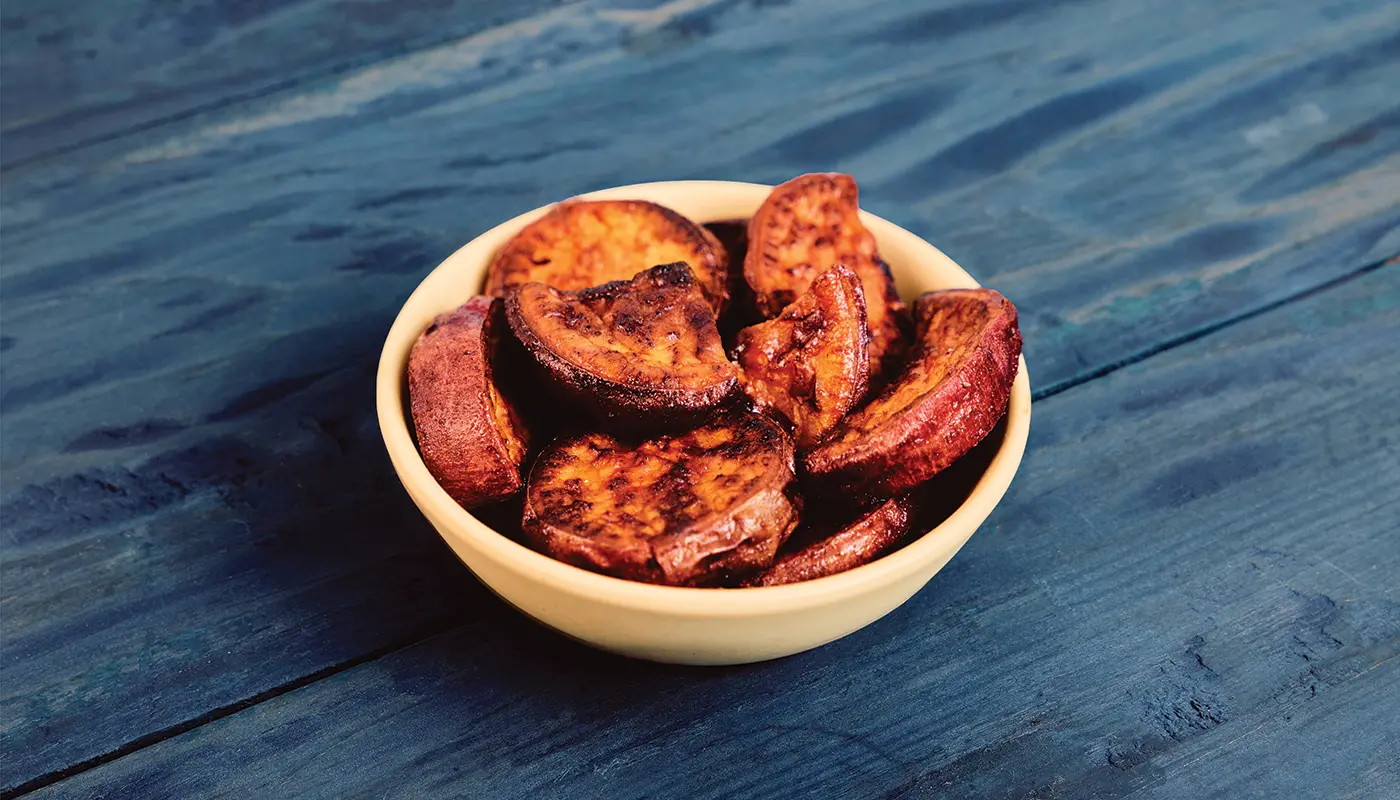 Roasted Sweet Potatoes in a bowl on blue wooden boards.