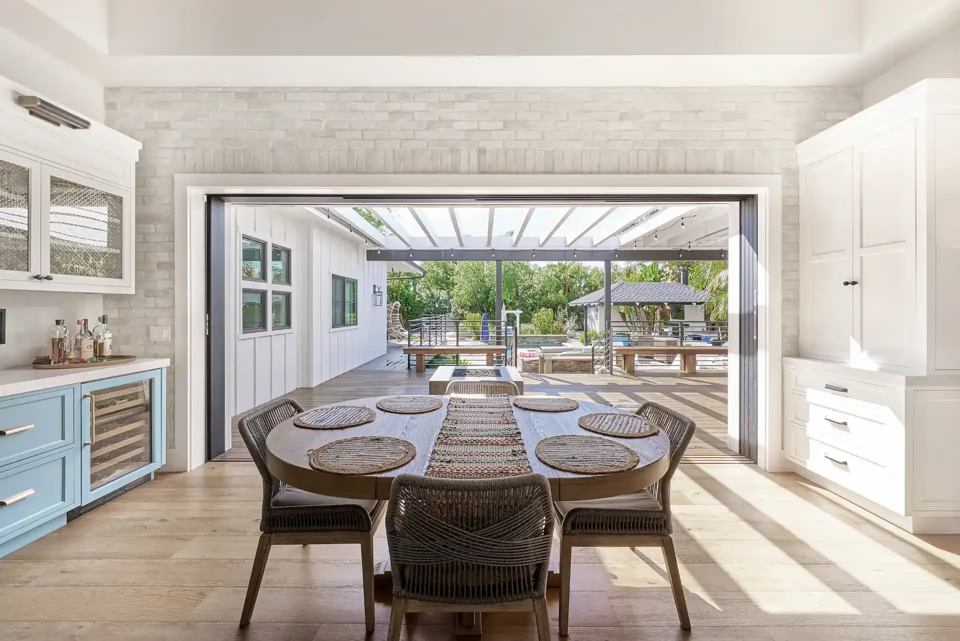 Full view of the living room from angle 2, featuring boho furniture and decor with a view of the backyard through French doors, blending indoor comfort with outdoor beauty. Photo by Todd Huge.