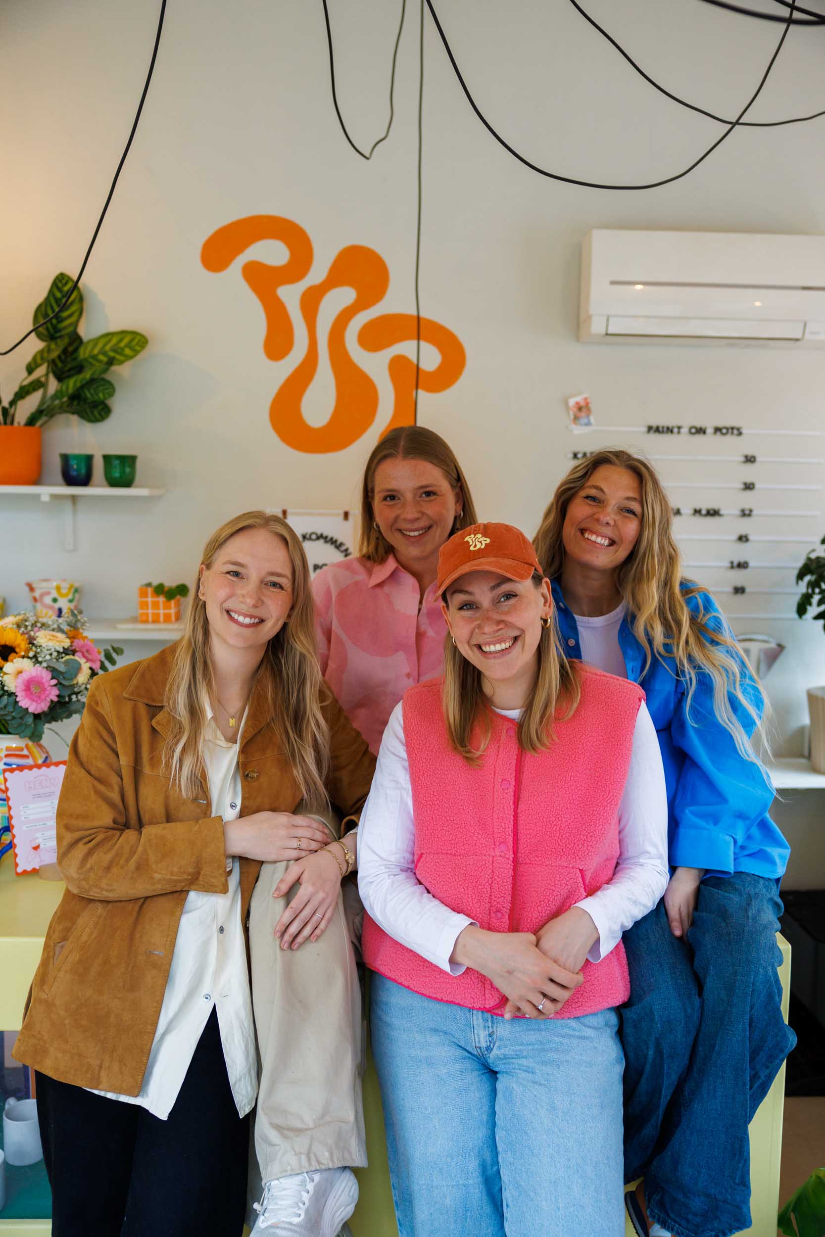 Fire ansatte i Paint on Pots sitter på disken og smiler mot kamera