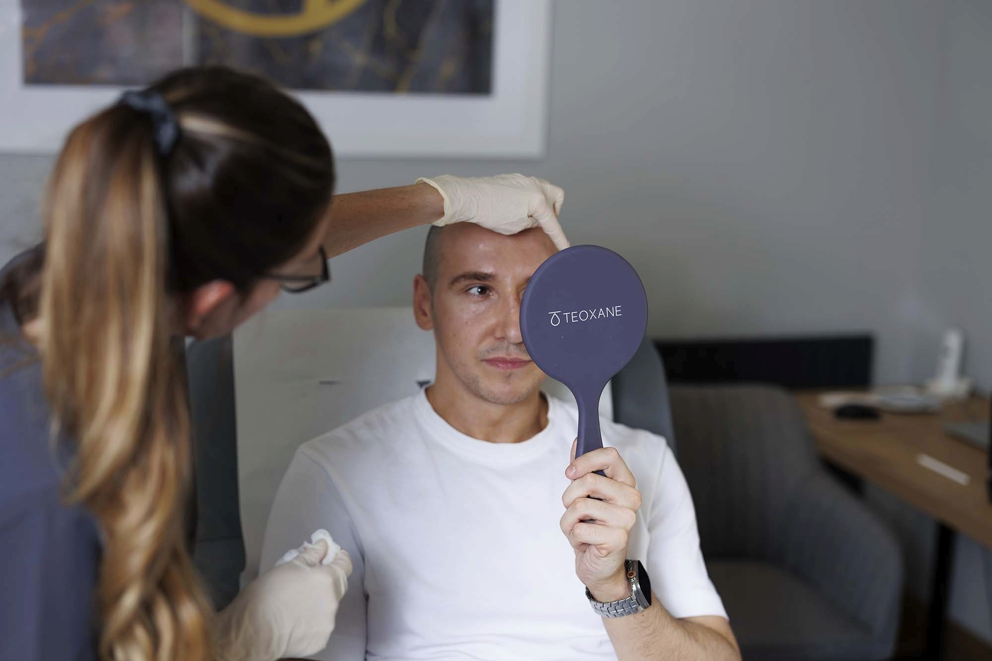 Man looking at himself in a hand held mirror during a skin treatment