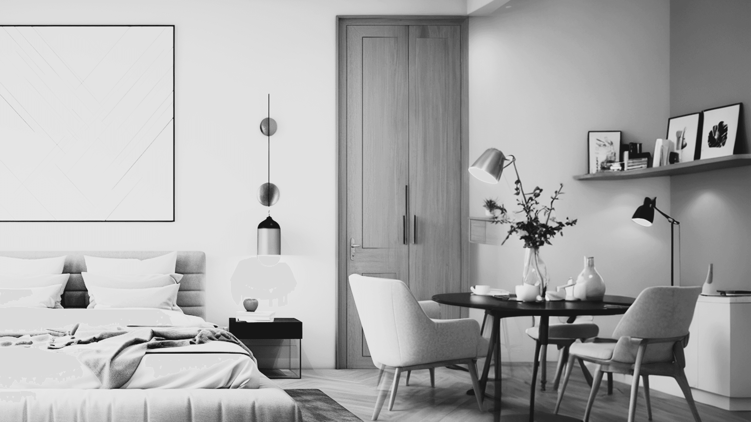 A black and white photo of a modern, minimalist bedroom with a bed, lamp, and a small workspace with a chair and wall decor.
