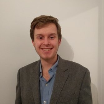 Mentor in rise research program for high school students, wearing glasses and suit – provides academic mentorship and supports summer research experiences.