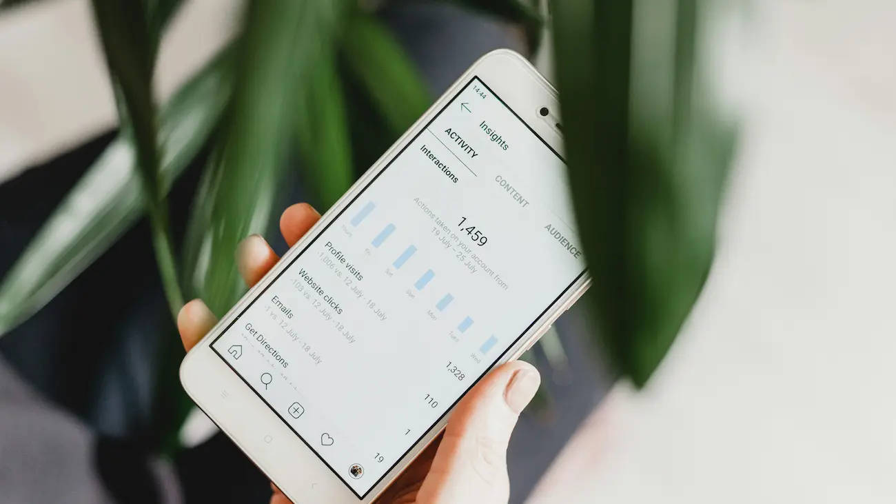 Person holding a smartphone displaying analytics and performance insights, representing sports sponsorship reporting, KPI tracking and measurable sponsor results for sports clubs.
