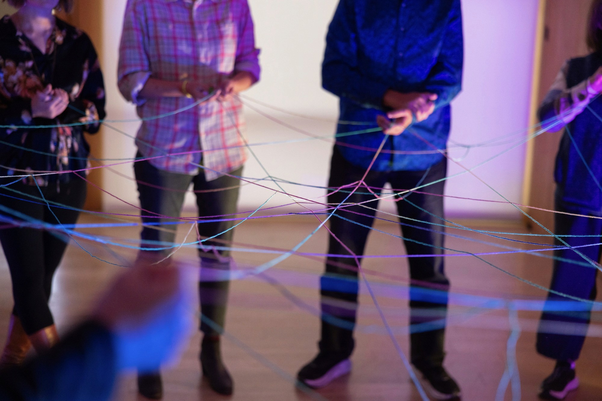 Several people holding string as a web at the Artificiality Summit 2025