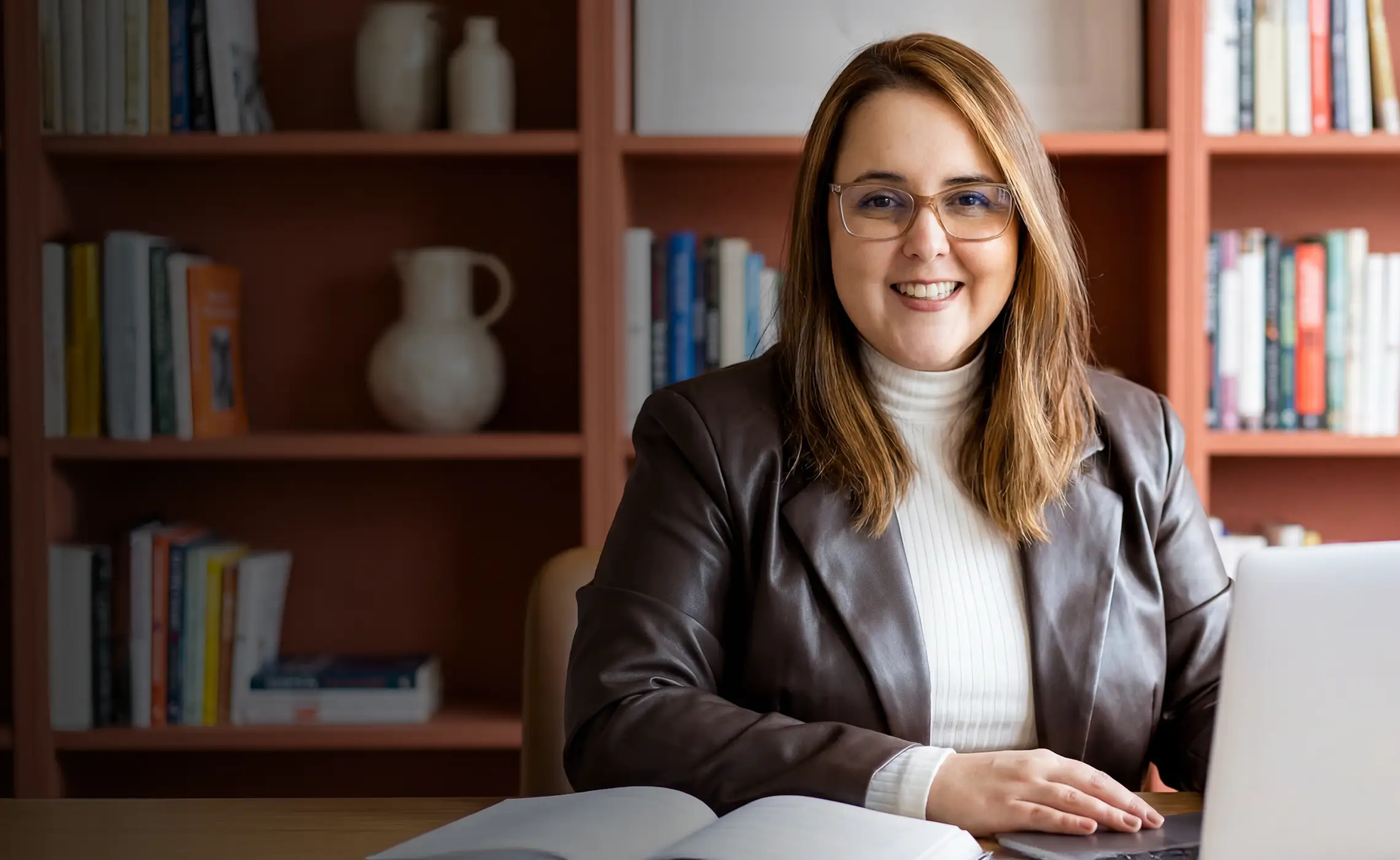 Nathalia Bittencourt, consultora de negócios, sorrindo em sua mesa de trabalho