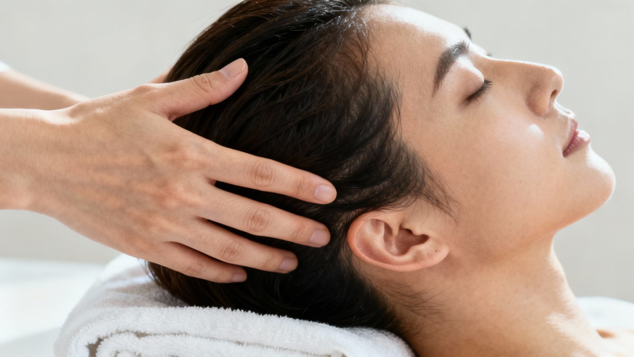 A serene woman enjoying a therapeutic scalp massage with closed eyes for relaxation.