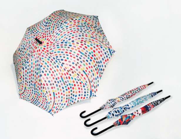 Three umbrellas are displayed against a white background. The largest umbrella features a multicolored polka dot pattern. To its right are two smaller umbrellas: one with a blue and white pattern and the other with a multicolored, abstract design. All umbrellas have black handles.