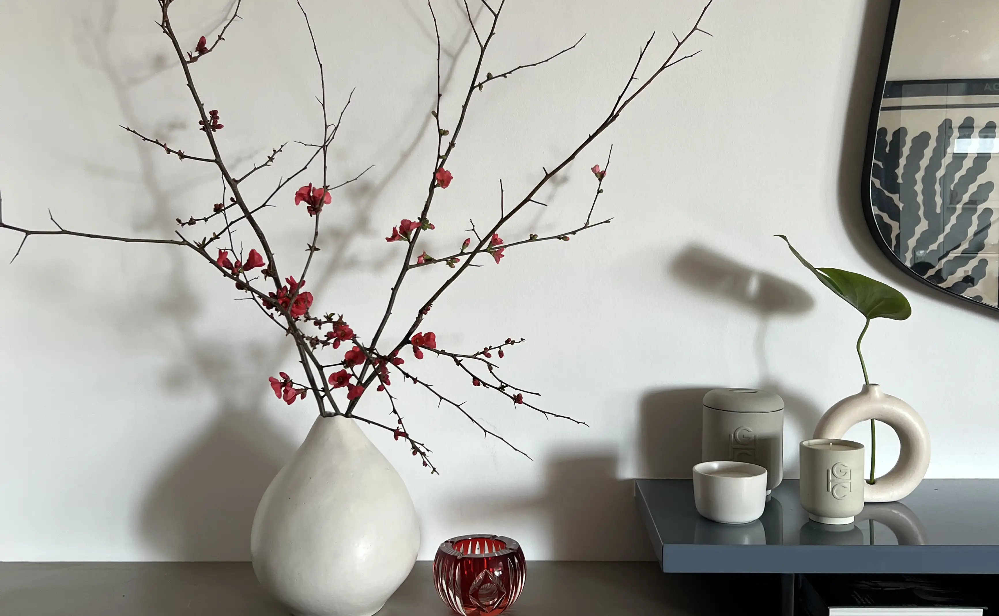 Composición con ramas floridas y cerámicas neutras para marcas de diseño que comunican equilibrio entre arte floral y minimalismo.