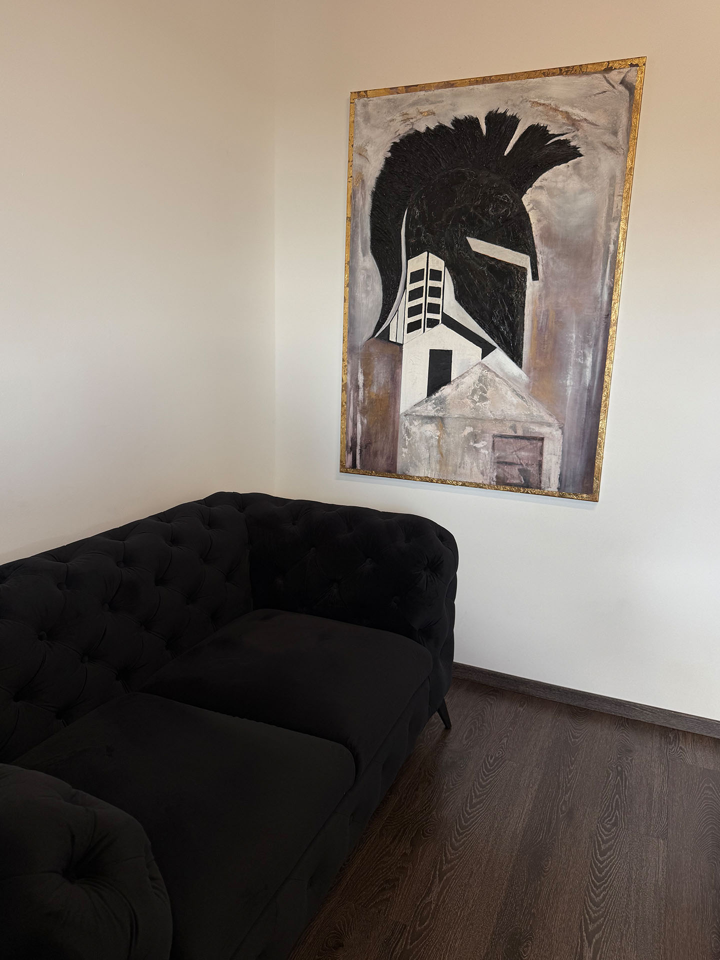 Modernes Kunstwerk mit Hausmotiv über einem schwarzen Samtsofa im Besprechungsraum