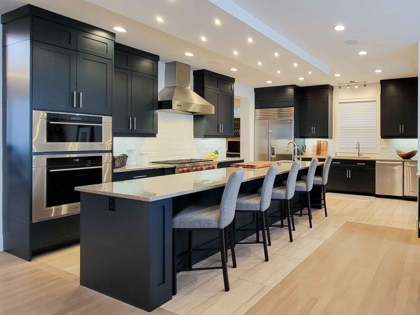 Image of Modern kitchen design with island seating, stainless steel appliances, and dark cabinets by KHD Homes.