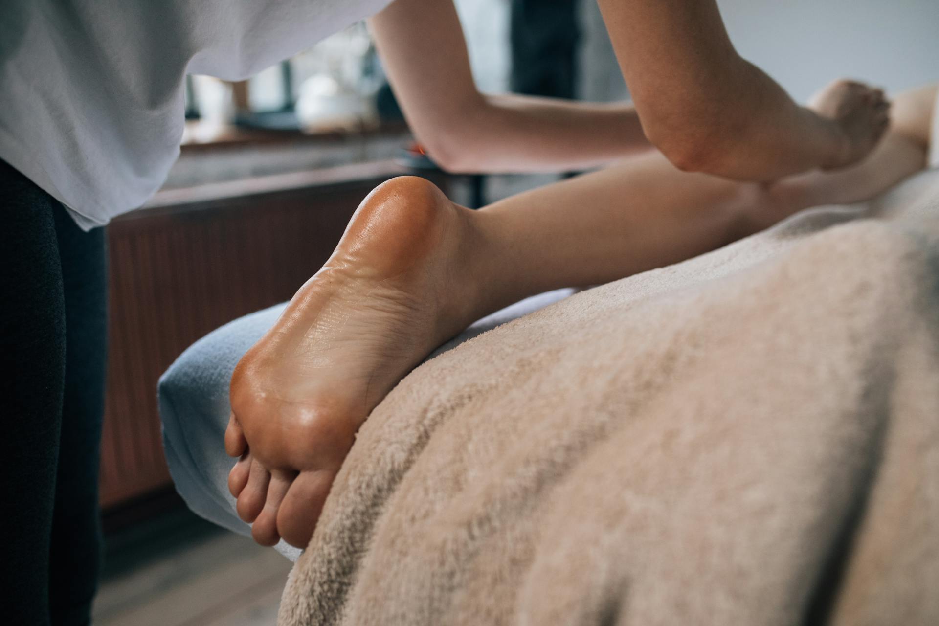 A stylist is doing a client's hair at the Camelia beauty salon. In one hand, they hold a hairdryer, and with the other hand, they adjust the hair.