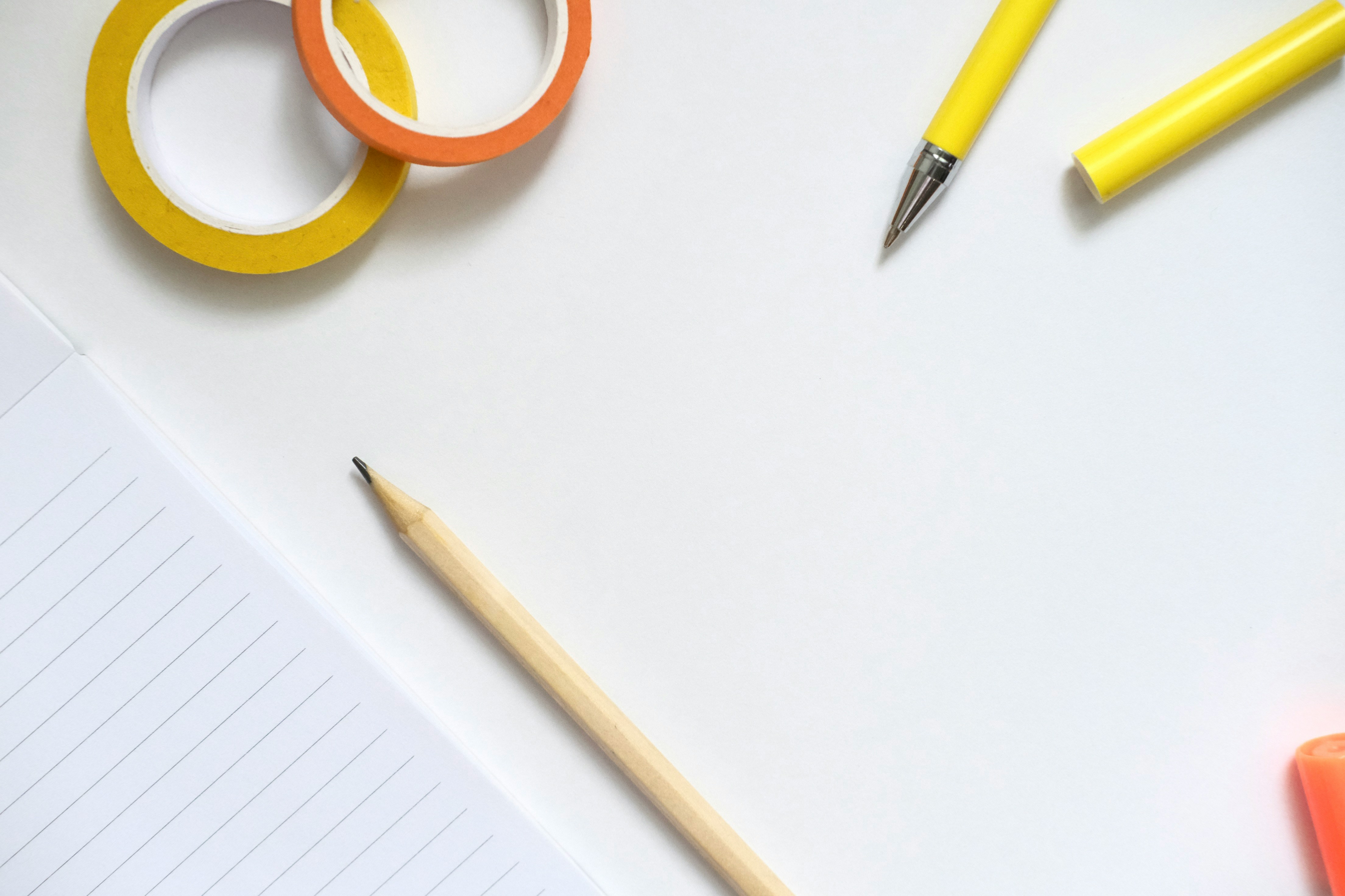 Yellow and orange tape with pens and pencil on white.