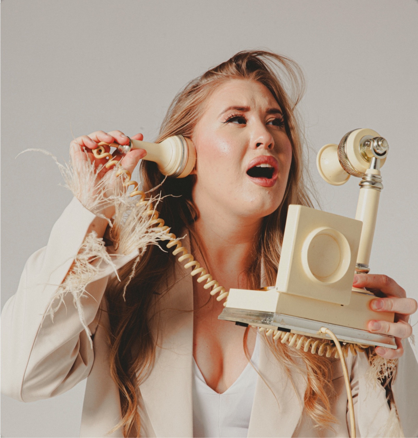 Ekspresyjne, stylizowane zdjęcie artystki agencji Music Shapes trzymającej słuchawki staromodnego telefonu retro – nastrojowa grafika w sekcji kontakt, zachęcająca do współpracy i zapytania o ofertę muzyczną.