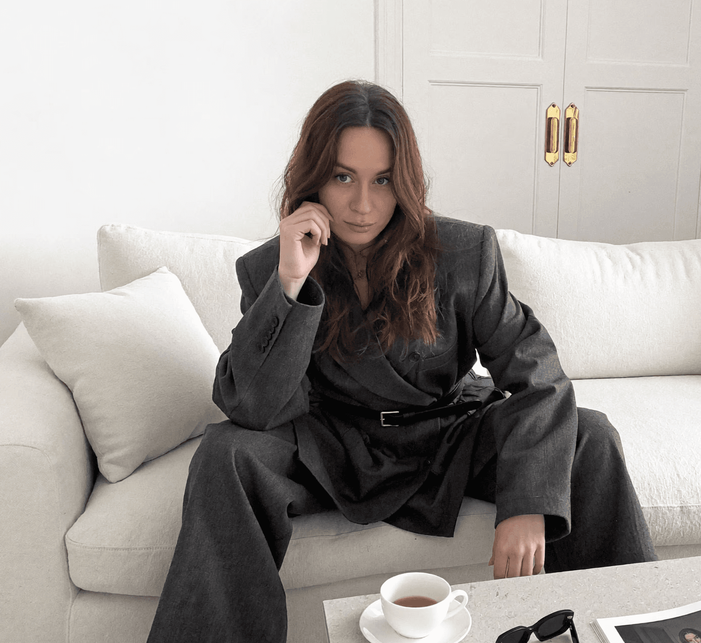 A stylish individual in a black shirt and silver pants stands against a blurred background, creating a dynamic and modern aesthetic.