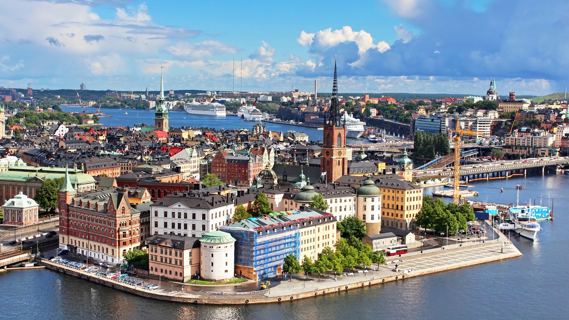A man stands while two people sit at a table in an office setting, smiling and engaged in conversation. The mood is friendly and collaborative.