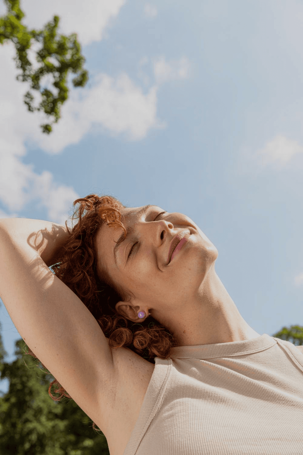 mujer sonriendo mientras mira hacia arriba a las nubes