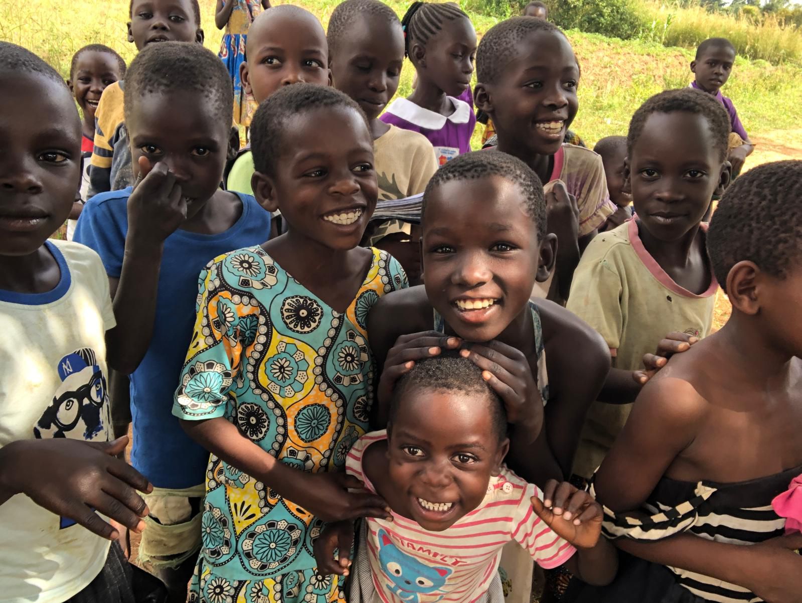 five children smiling while doing peace hand sign