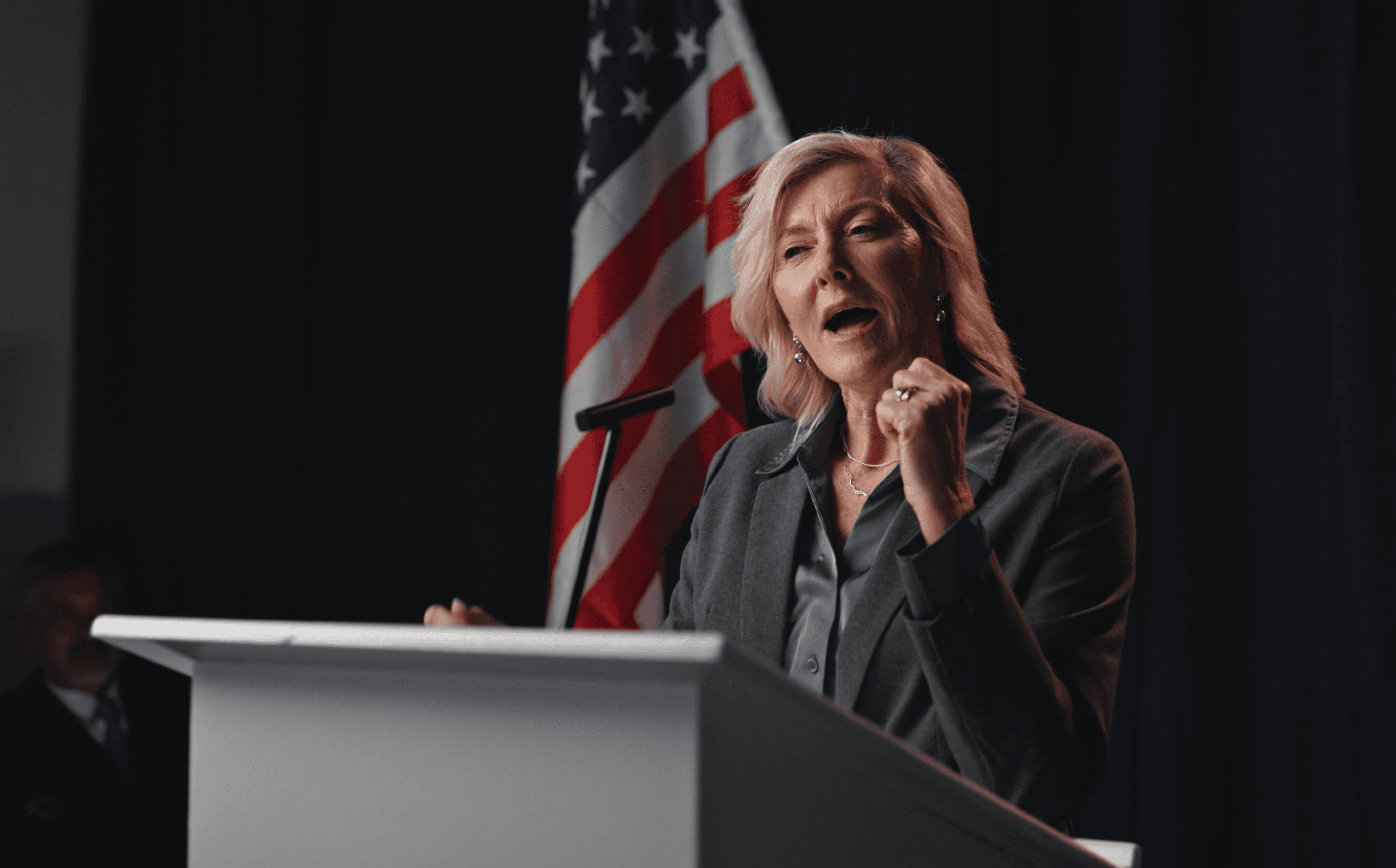 Candidate speaking at a podium in front of the flag