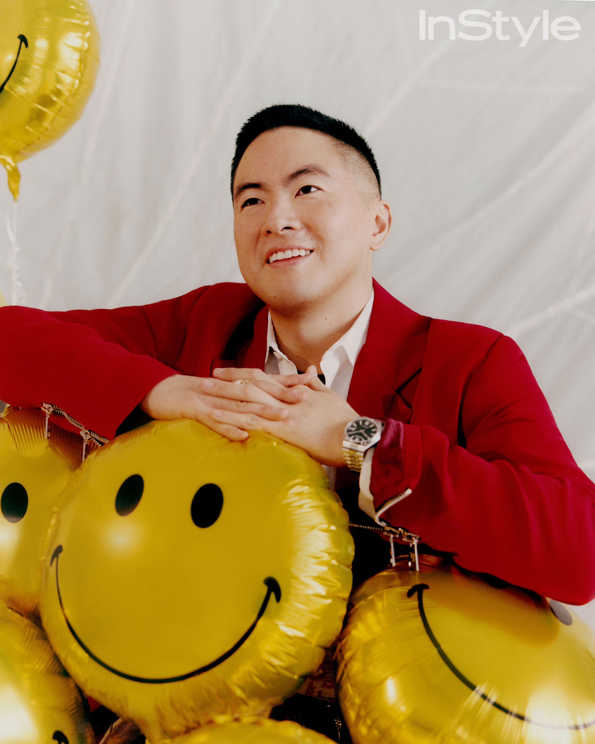Bowen Yang with gold smiling balloons for InStyle