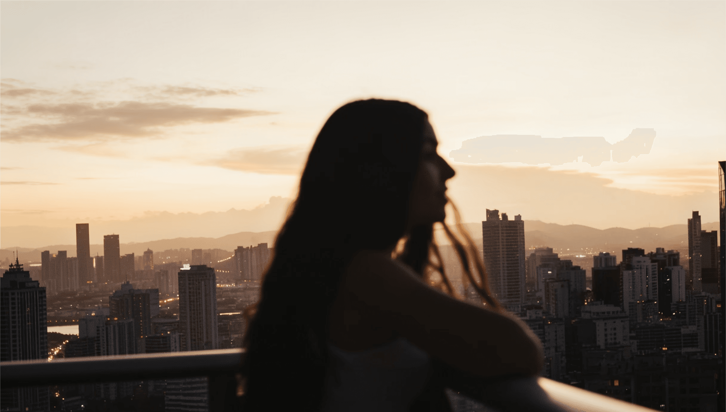 Frauensilhouette vor Stadtpanorama bei Sonnenuntergang – Dreambooster Nutzerin