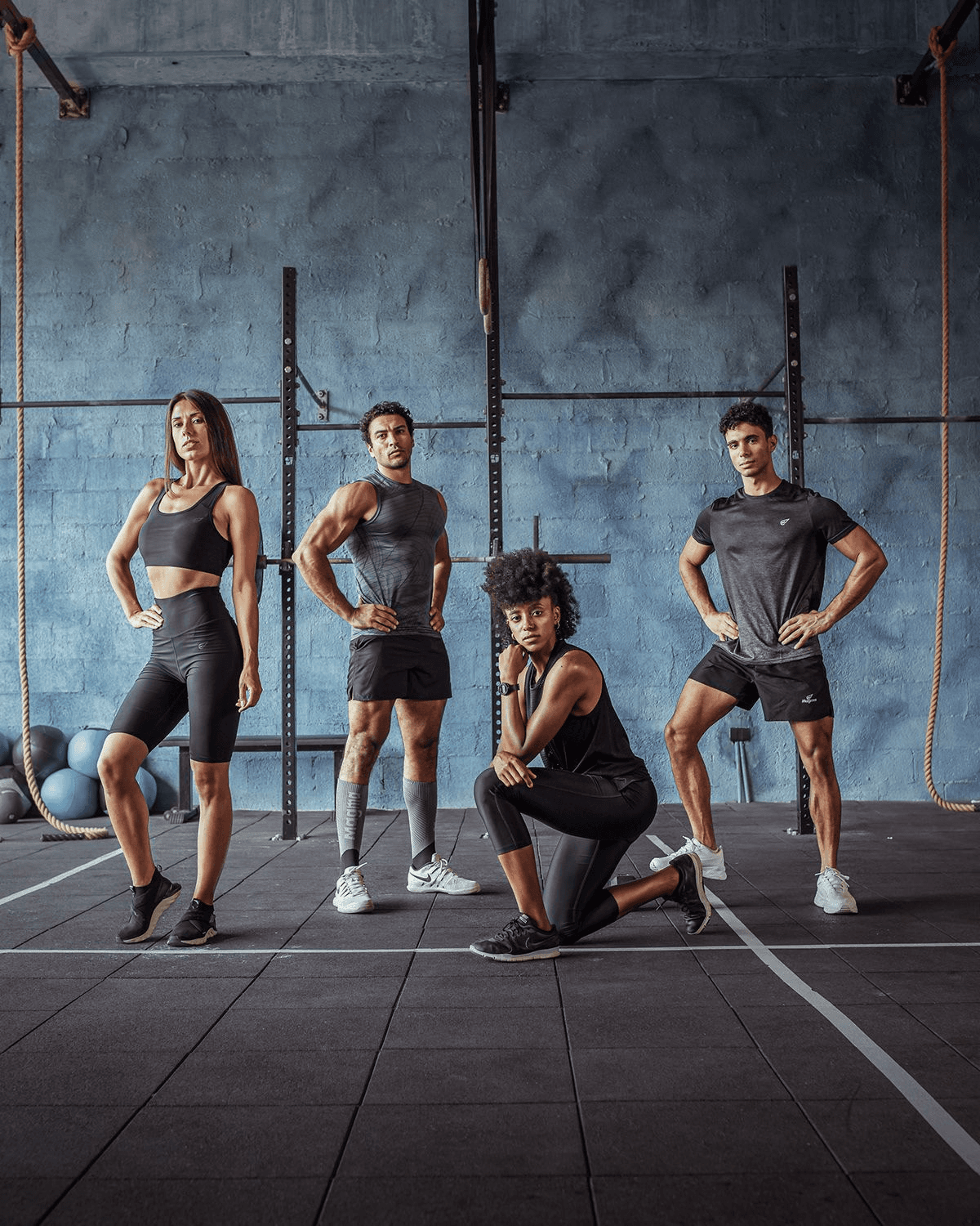 Four fit athletes posing confidently together in a modern gym.