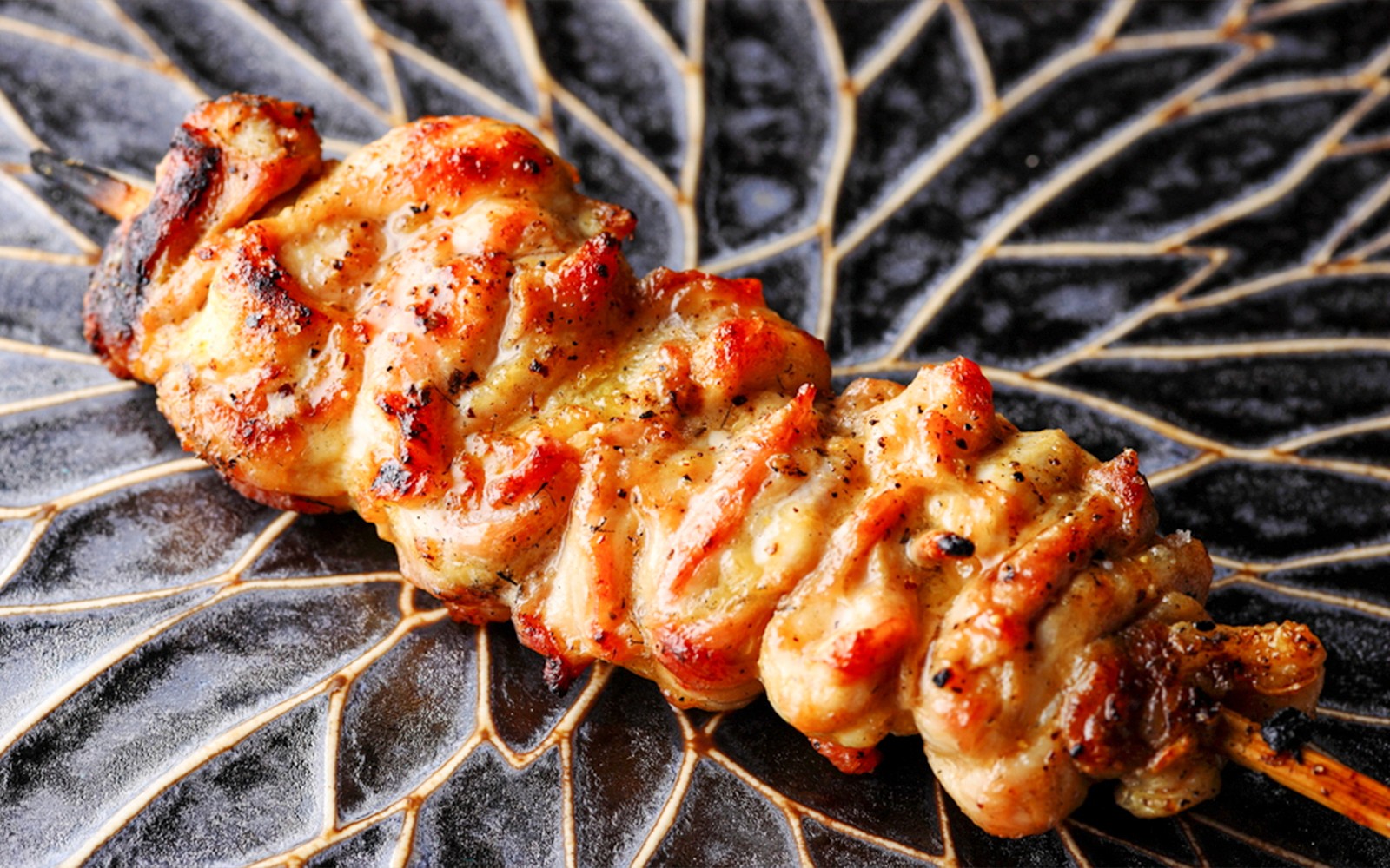 Yakitori chef grilling skewers at Yakitori Tsukiya in Tokyo for 6/9-course meal.