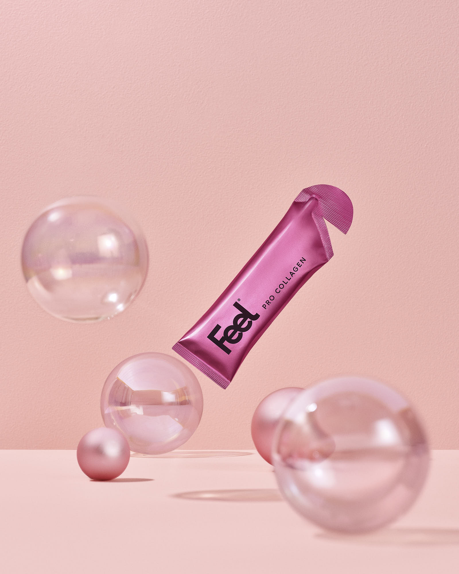 A pink tube amongst transparent bubbles, set against a soft pink background.