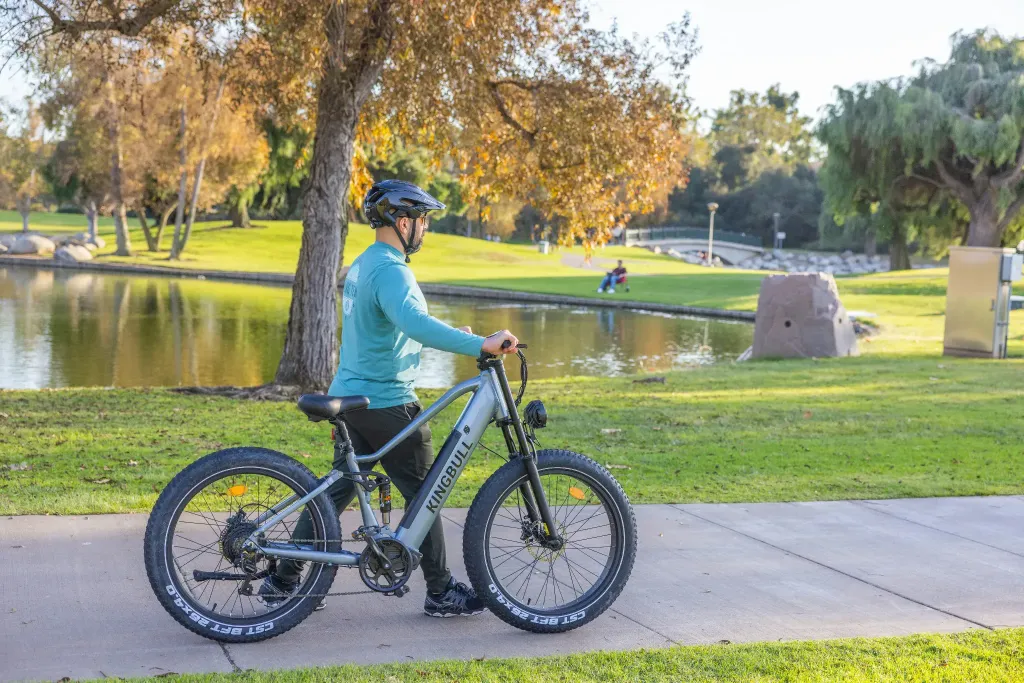 a man riding a bike down a sidewalk next to a lake