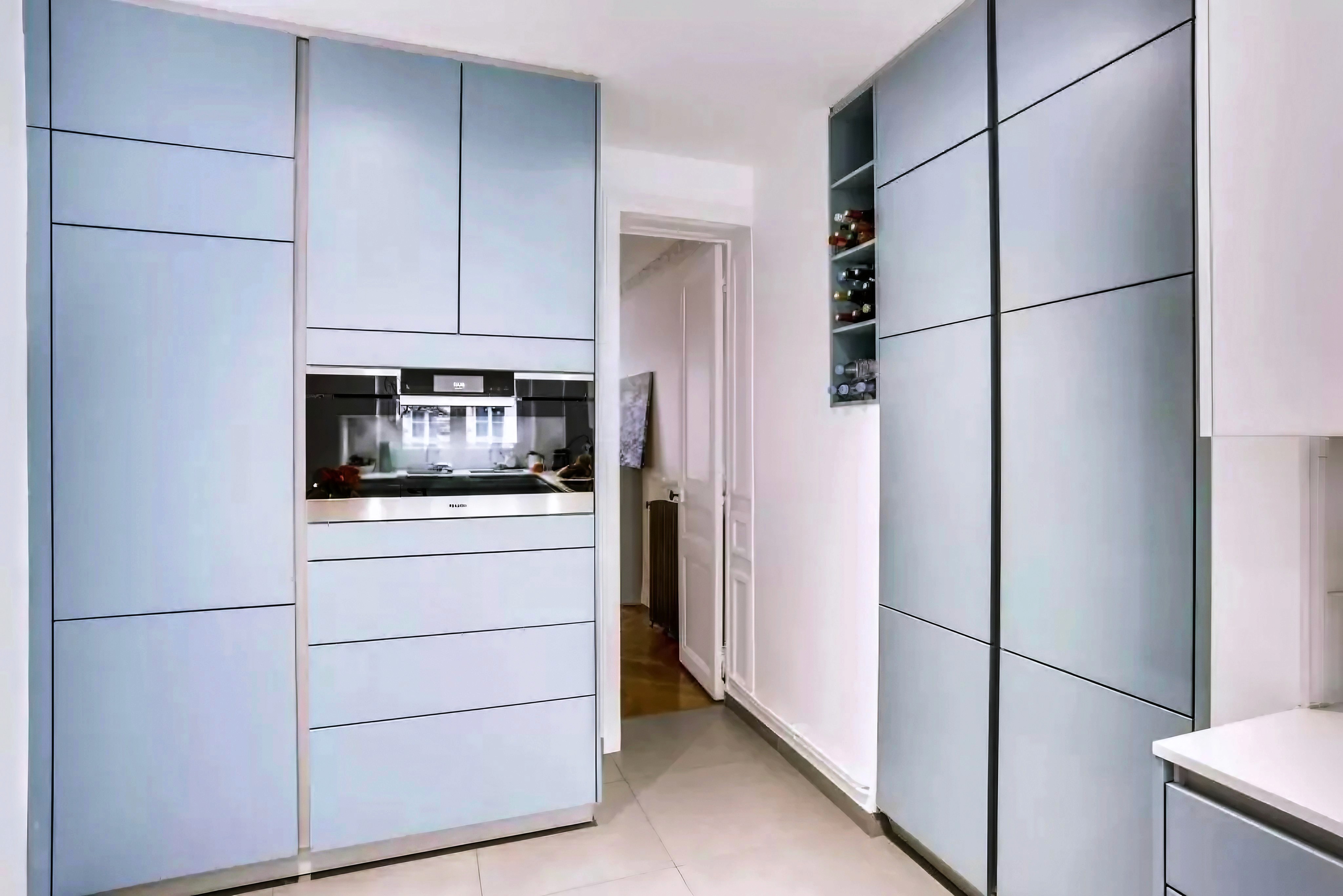 Rénovation cuisine épurée Paris Est avec armoires bleu clair, design minimaliste, sol carrelé neutre et nombreux rangements, architecte d'intérieur.