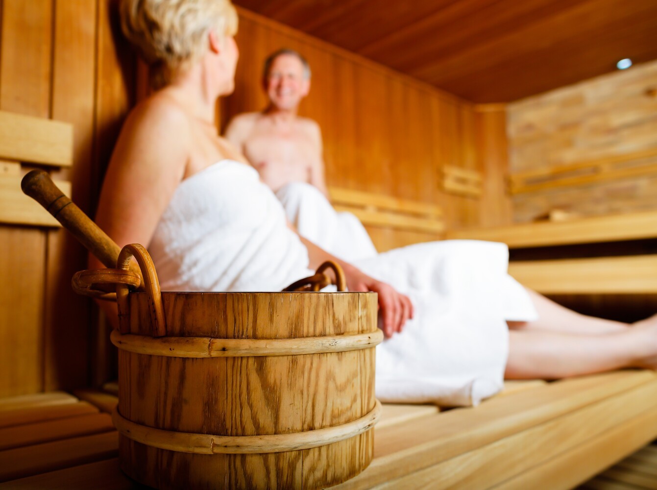 senior couple enjoying the increased calorie burn of a sauna to show the comparison of steam room vs sauna for weight loss