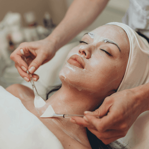 A woman lying down getting a facial with brushes on her neck