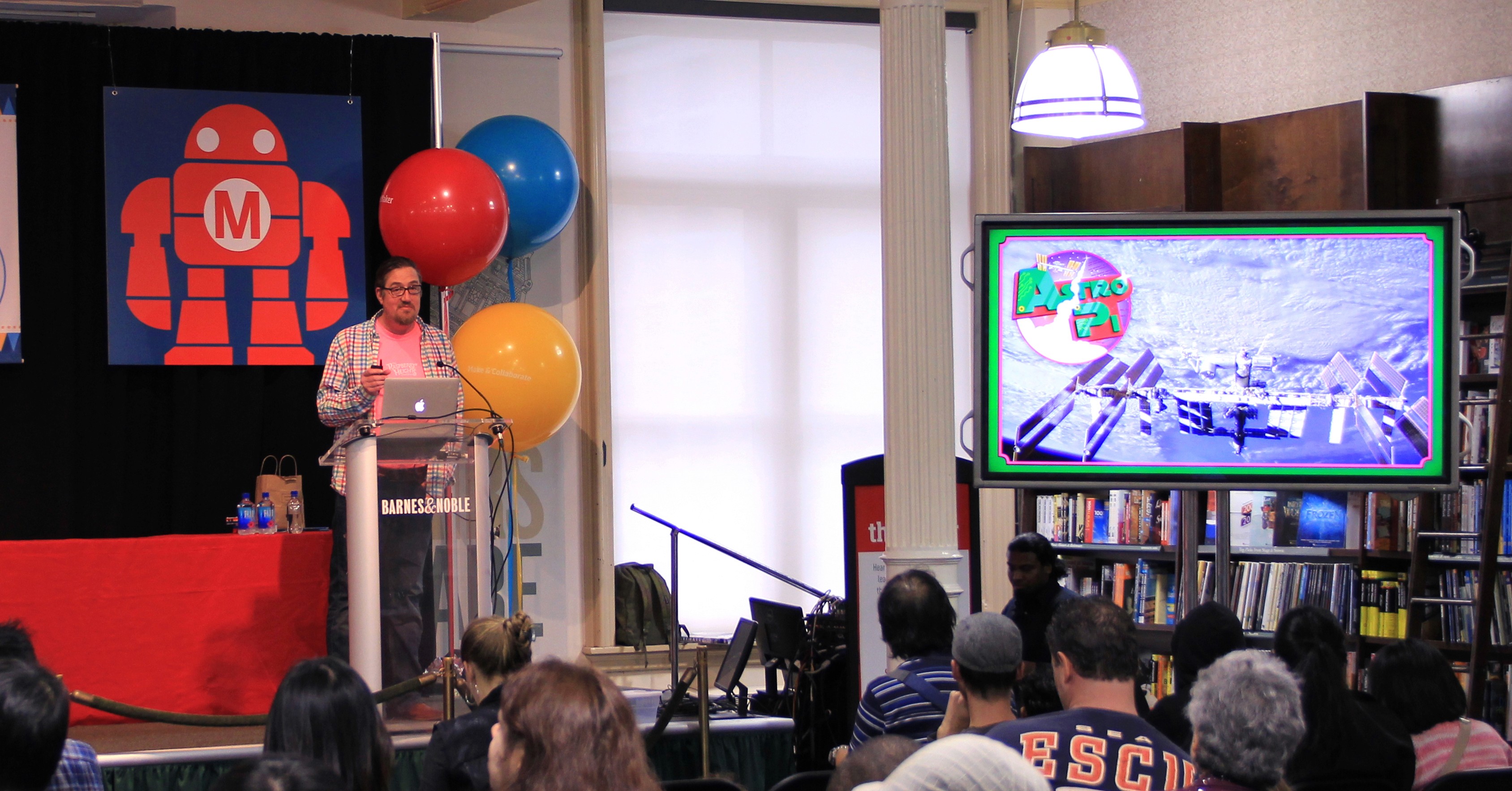 A photo of a group of people listening to a lecture and watching something on a tv screen.