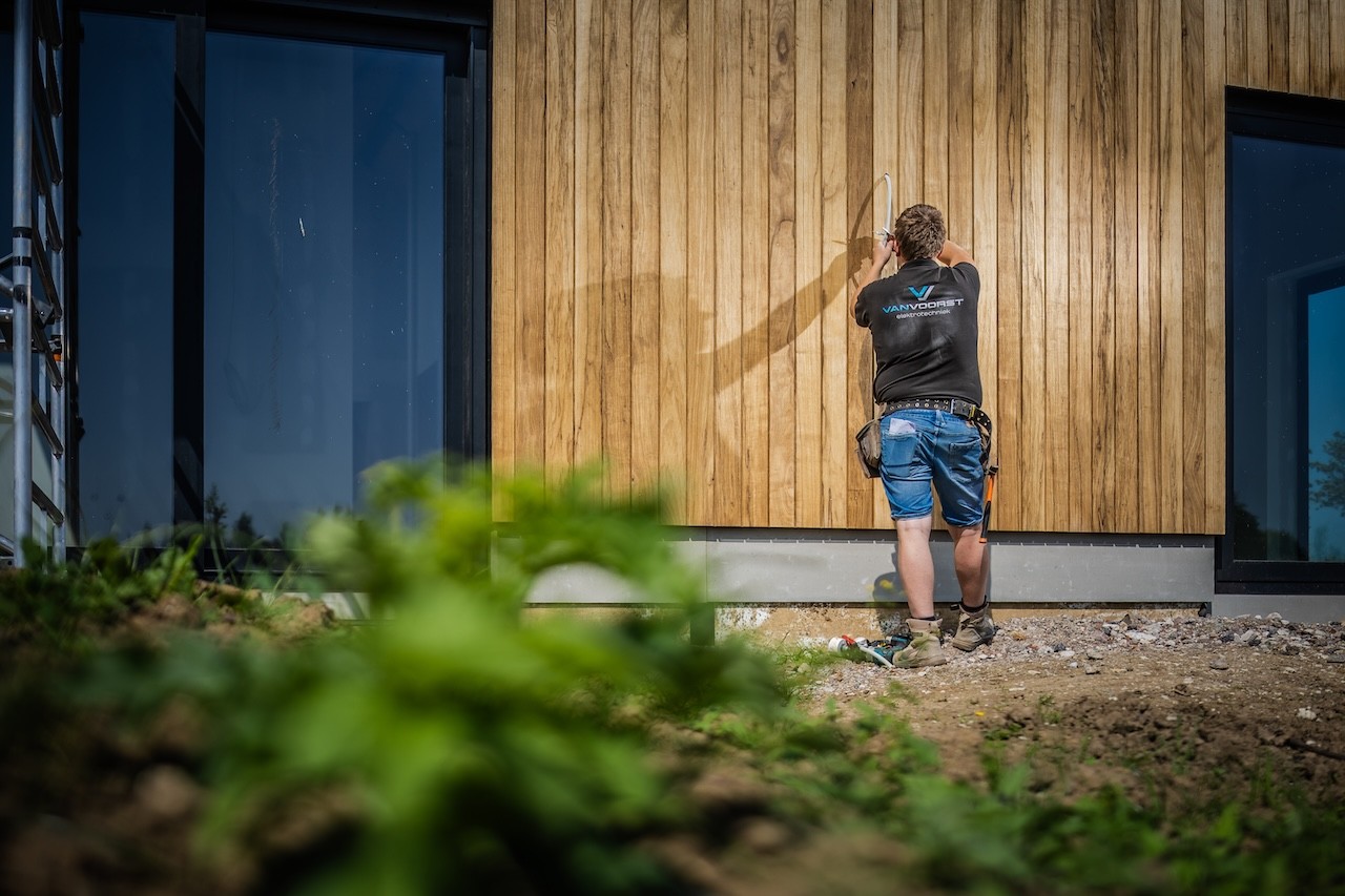 Medewerker Van Voorst Elektrotechniek sluit buitenverlichting aan bij klant
