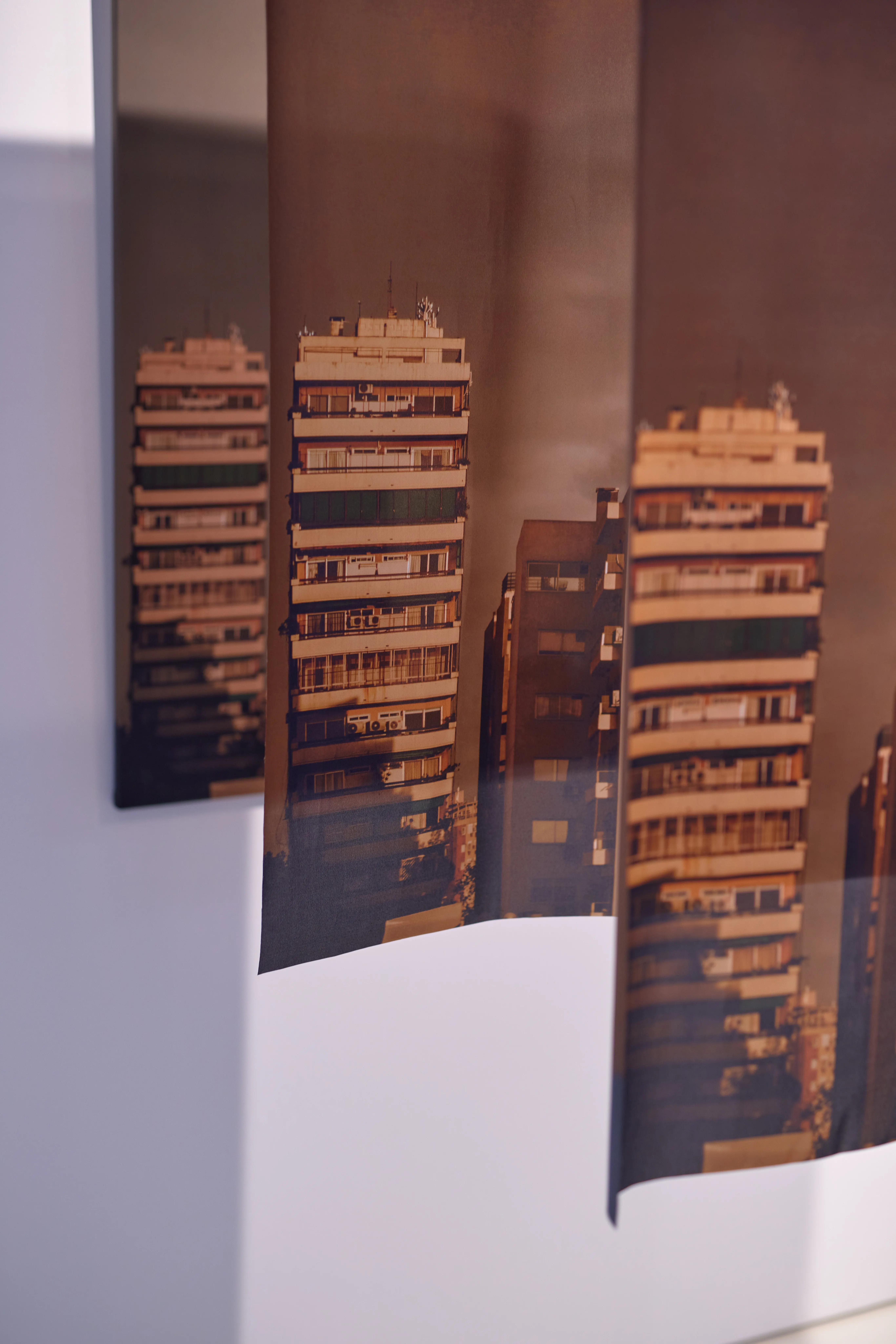Detail of suspended photo prints showing warm-toned high-rise facades at the AGU brand exhibition.