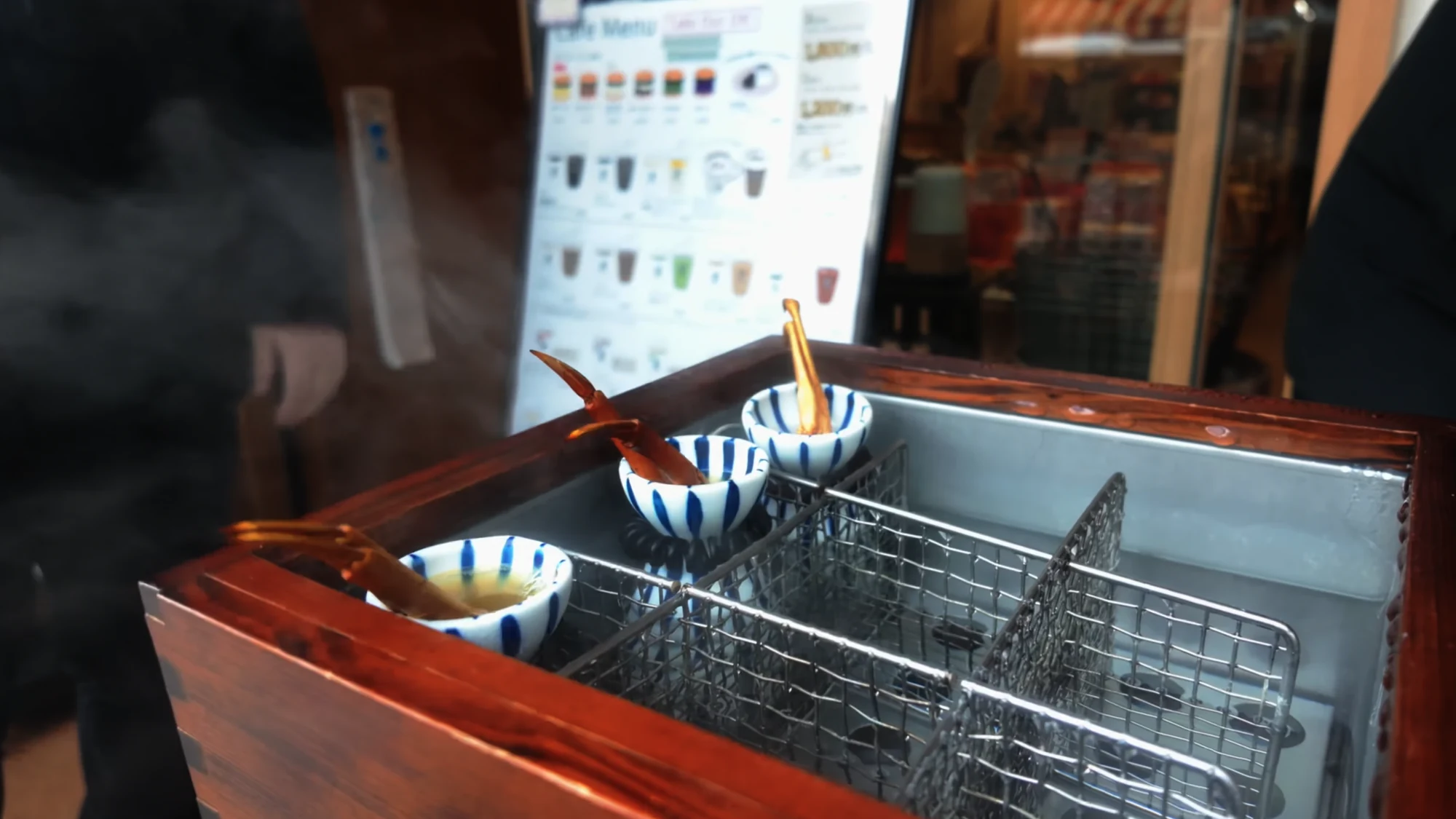 Striped bowls and wire baskets on the timber frame of the Kinosaki egg-boiling pit in winter.