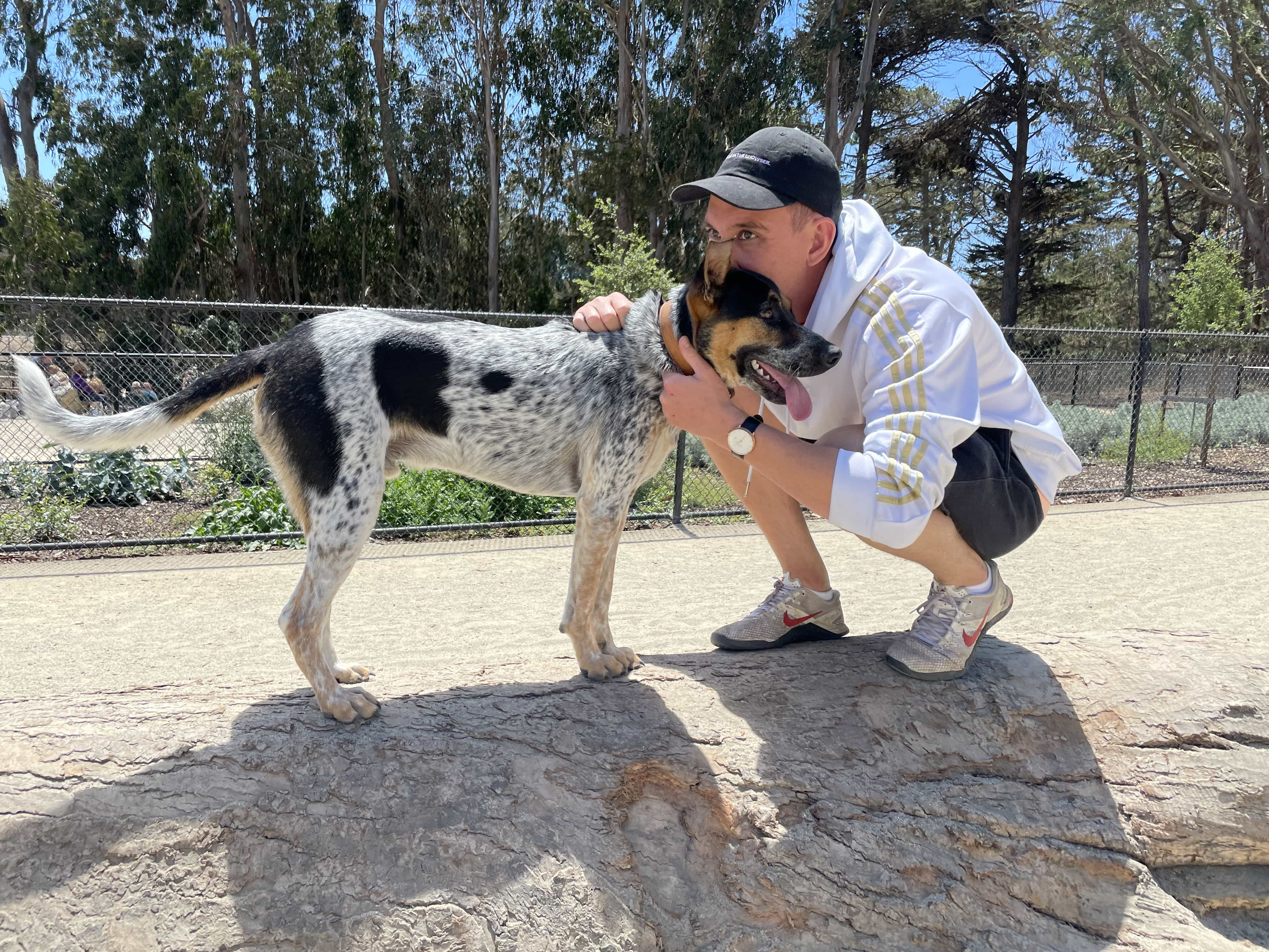 Zach and his dog Zazu squating in a park.