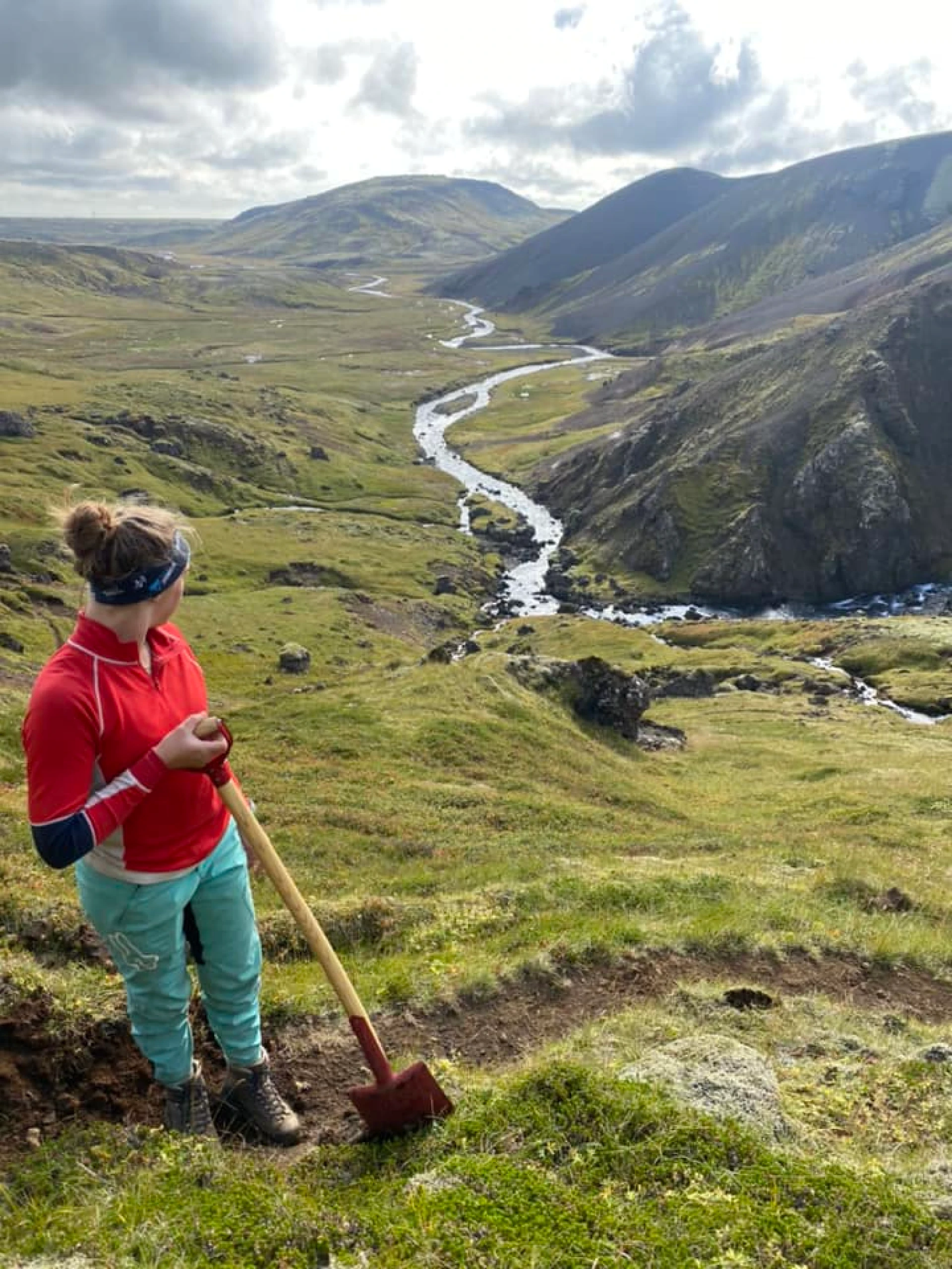 Woman trailbuilding on a green mountain