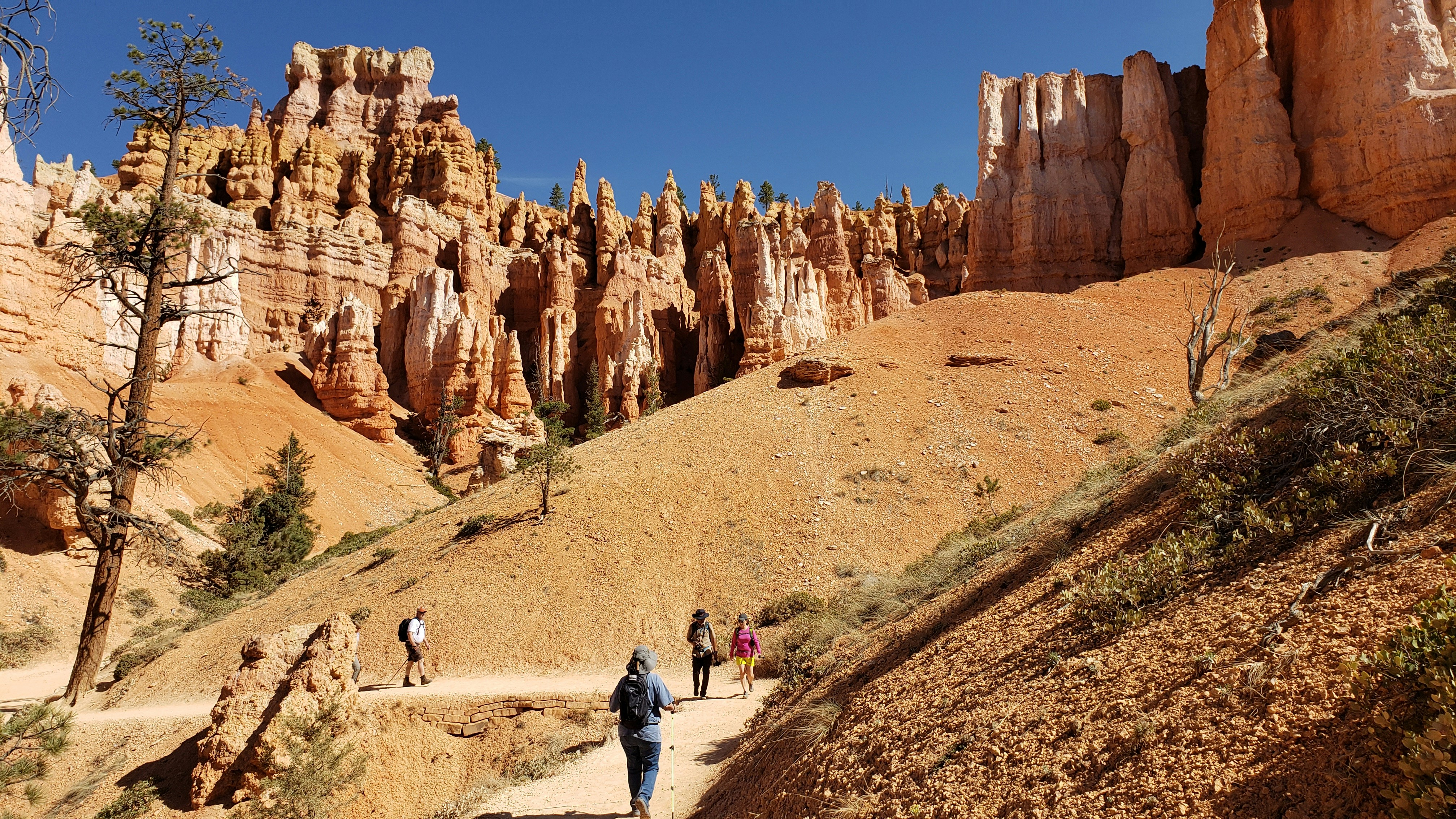 people walking on brown dirt road near brown rock formation during daytime