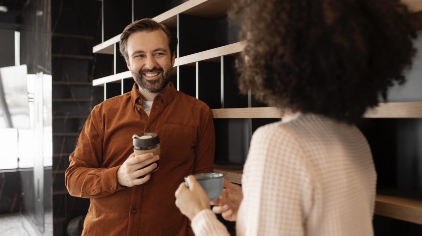 Two people talking friendly at a coffee machine