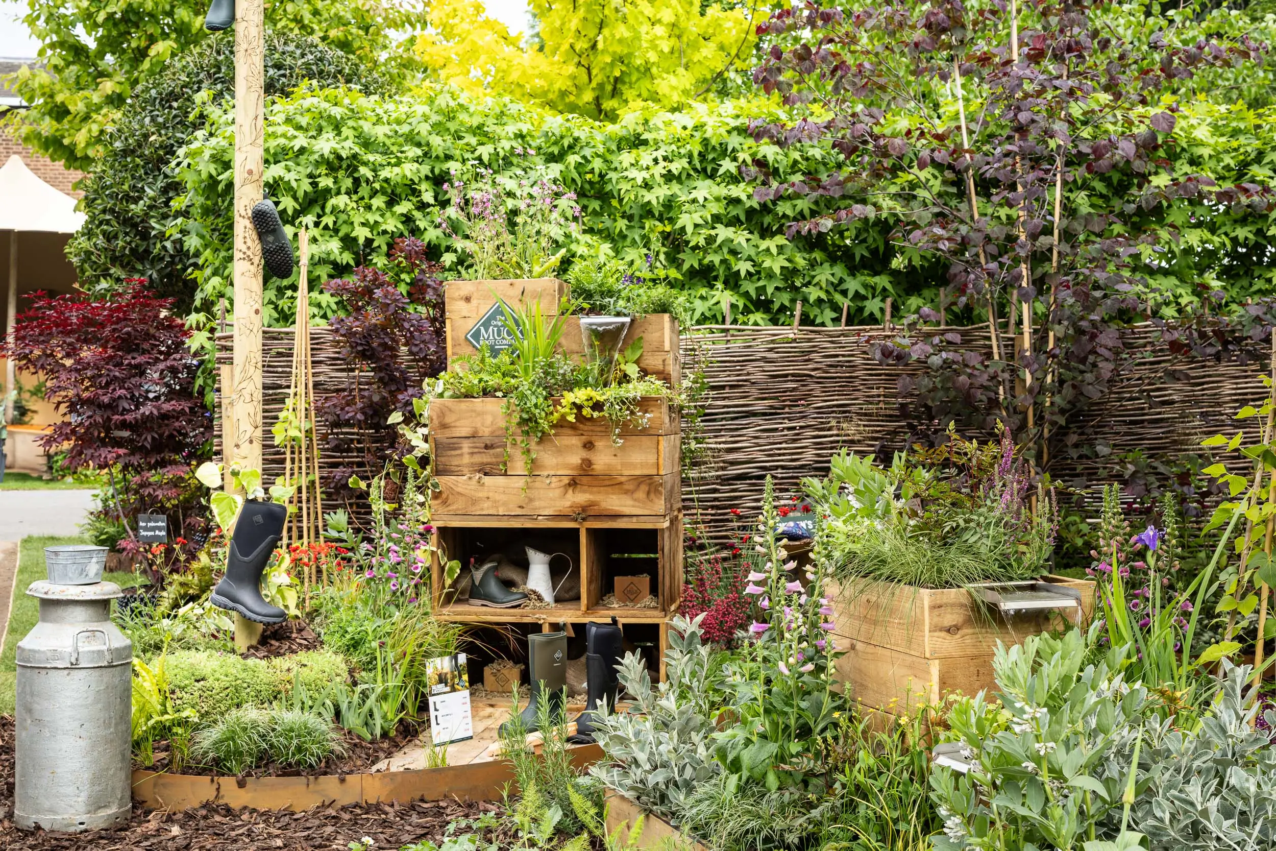 Lush garden scene with various plants, trees, and a small wooden structure, creating a tranquil, green space.