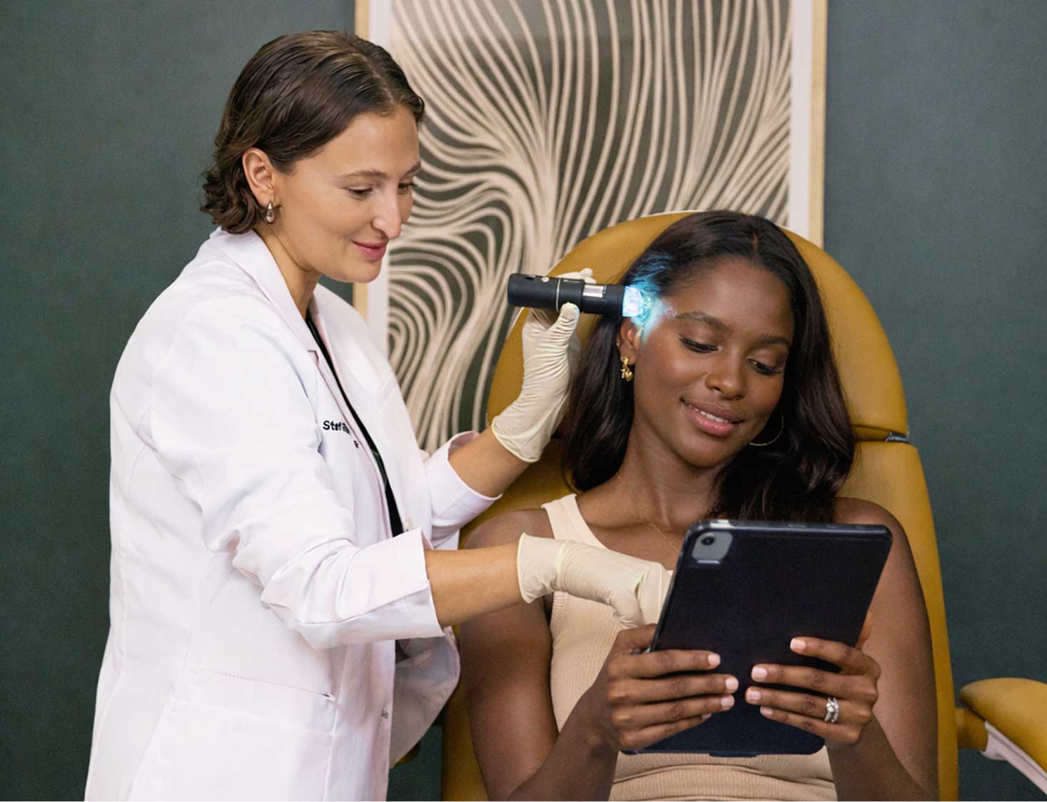 A hair care professional applying a treatment to a client's scalp in a salon setting.
