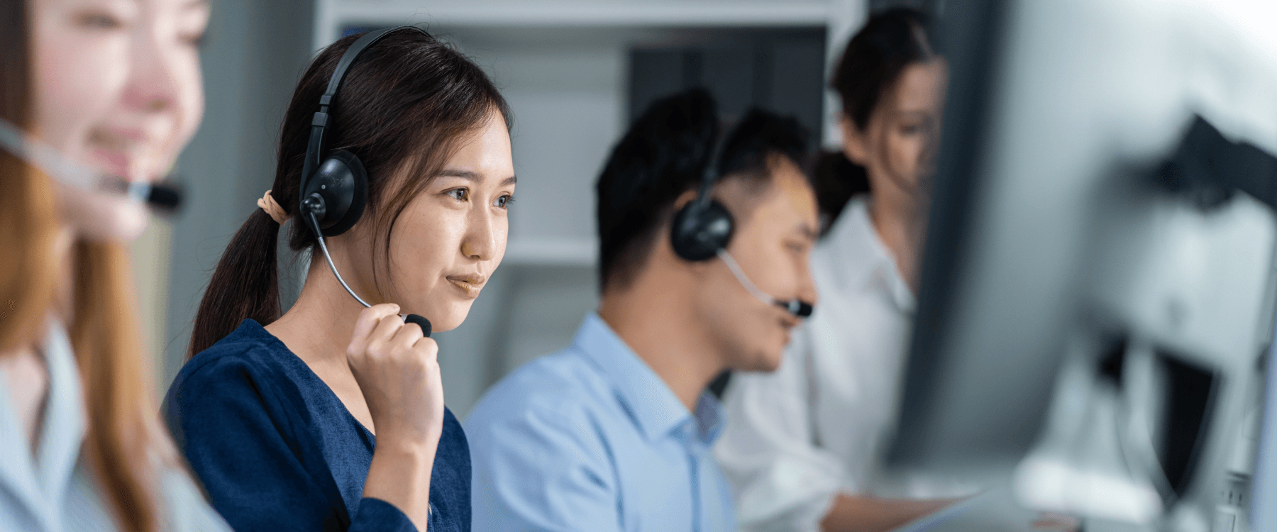 Equipe de atendimento usando headsets e computadores no Help Desk