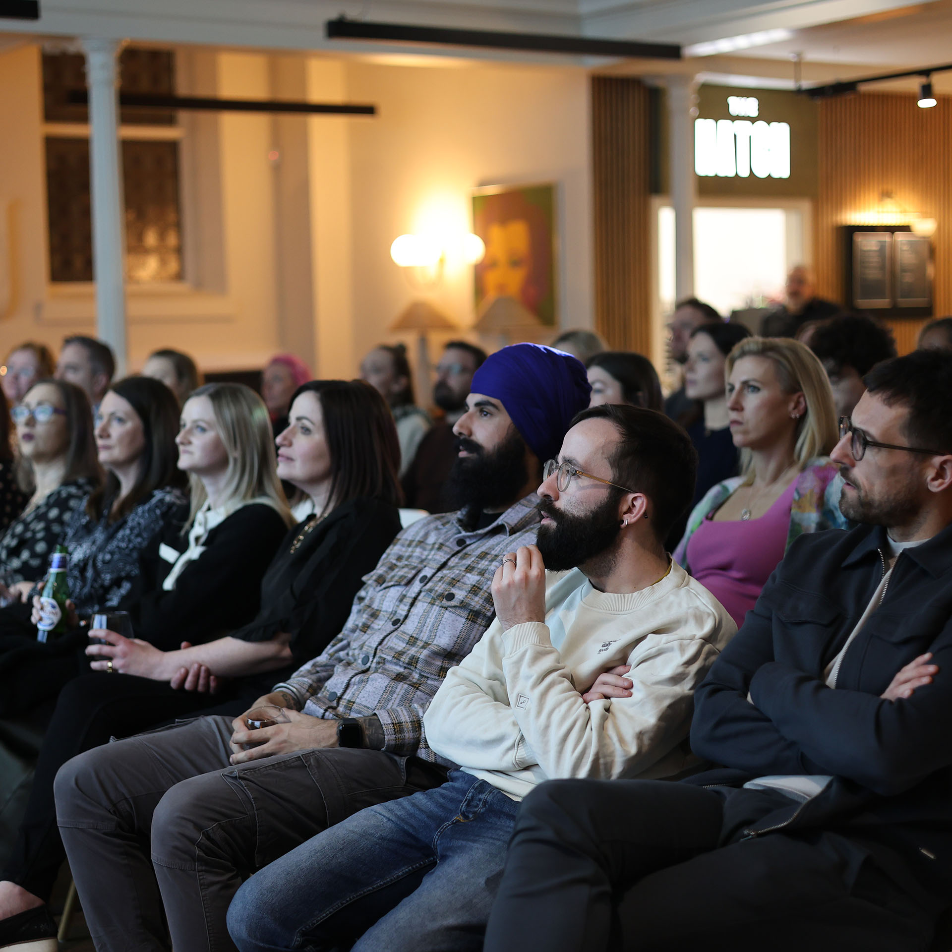 A group of people sat in rows of chairs watching a presentation