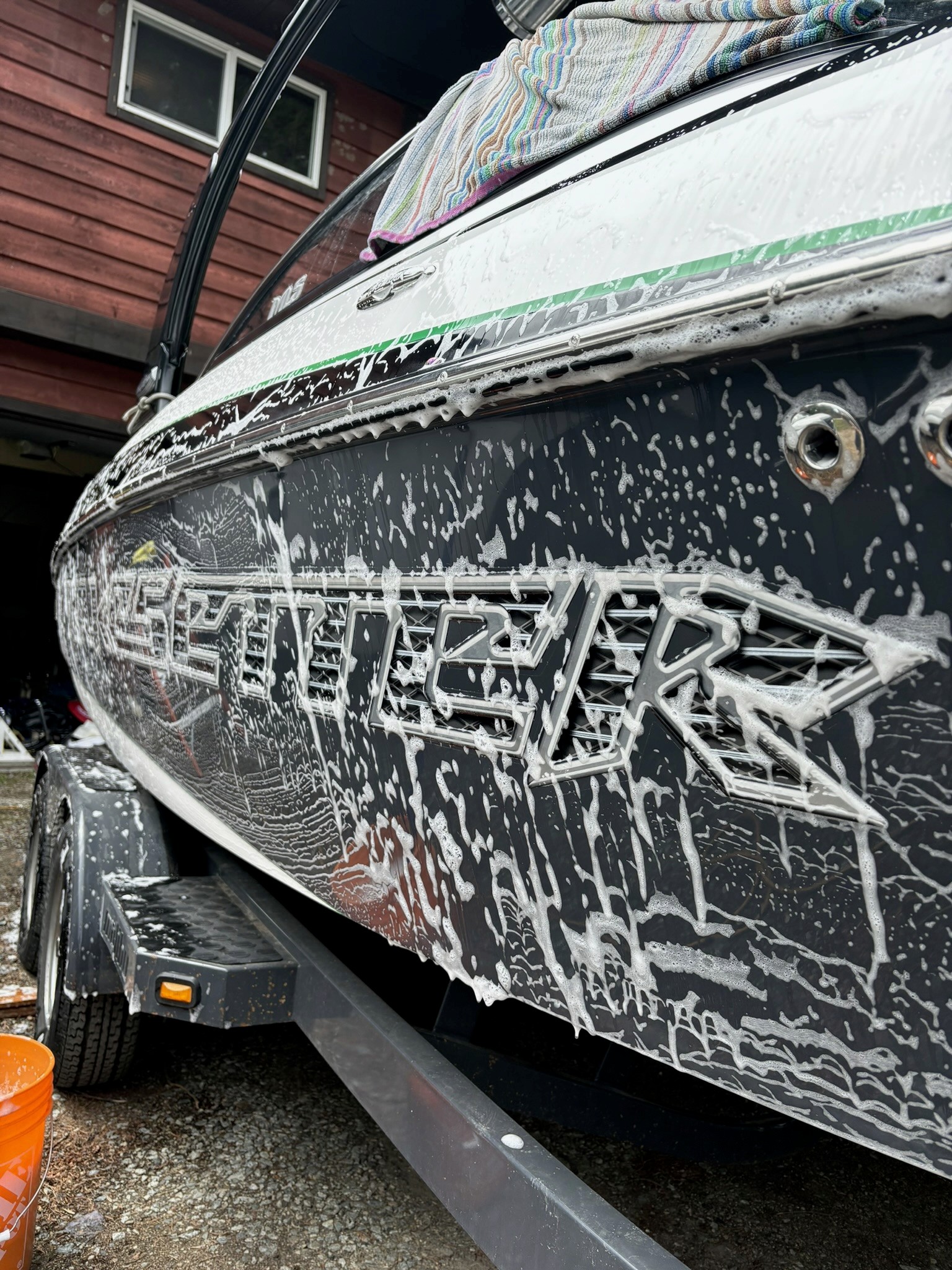 The side of a boat covered in sudsy soap ready to be detailed and cleaned