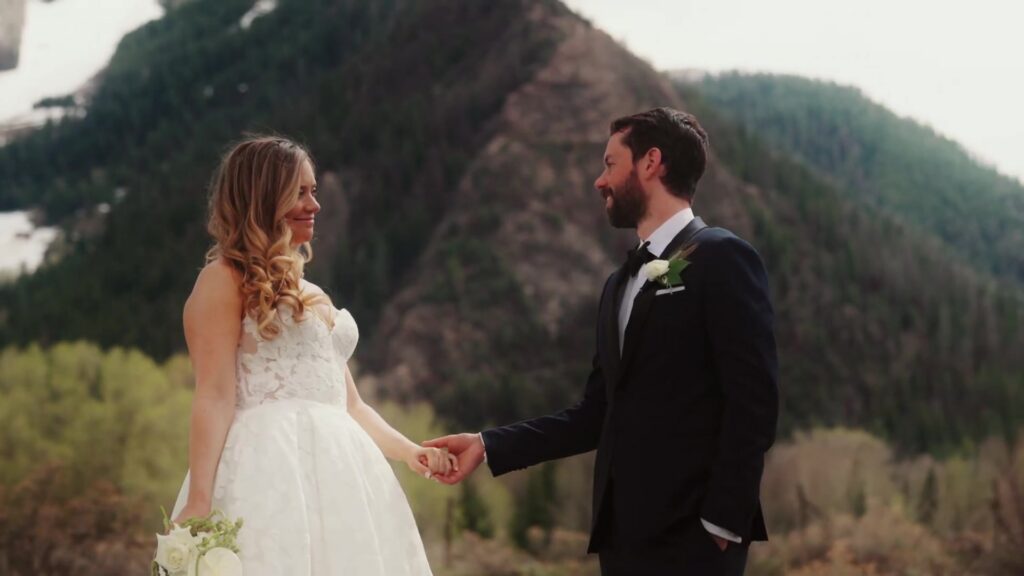 Couple holding hands with forested mountains behind them