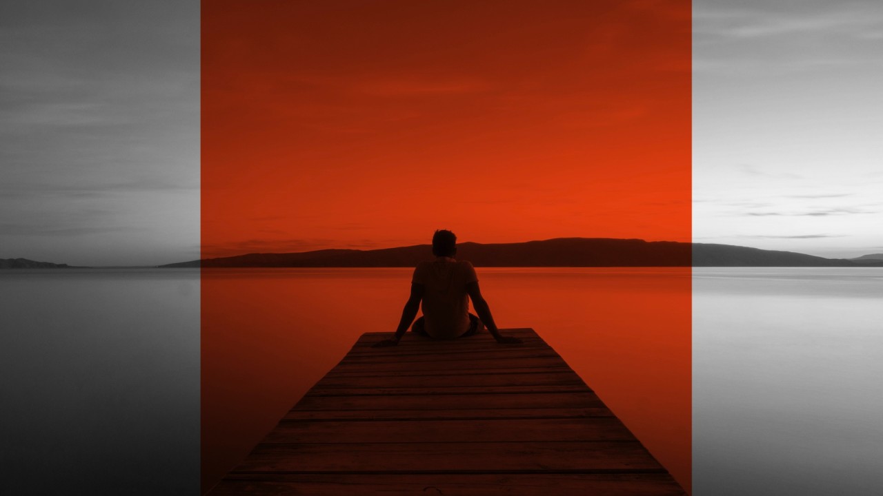 A person sitting pensively at the end of a pier