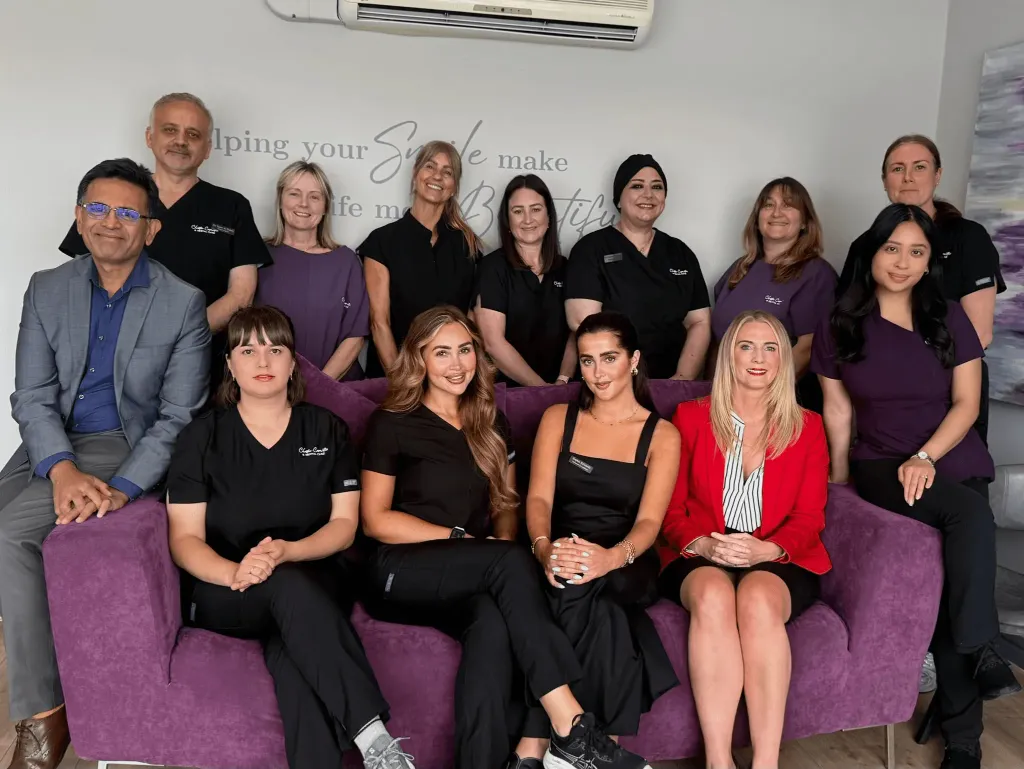 The Team of Dentist and Nurses at Chester Cosmetics & Dental Care sat on a couch and some standing behind