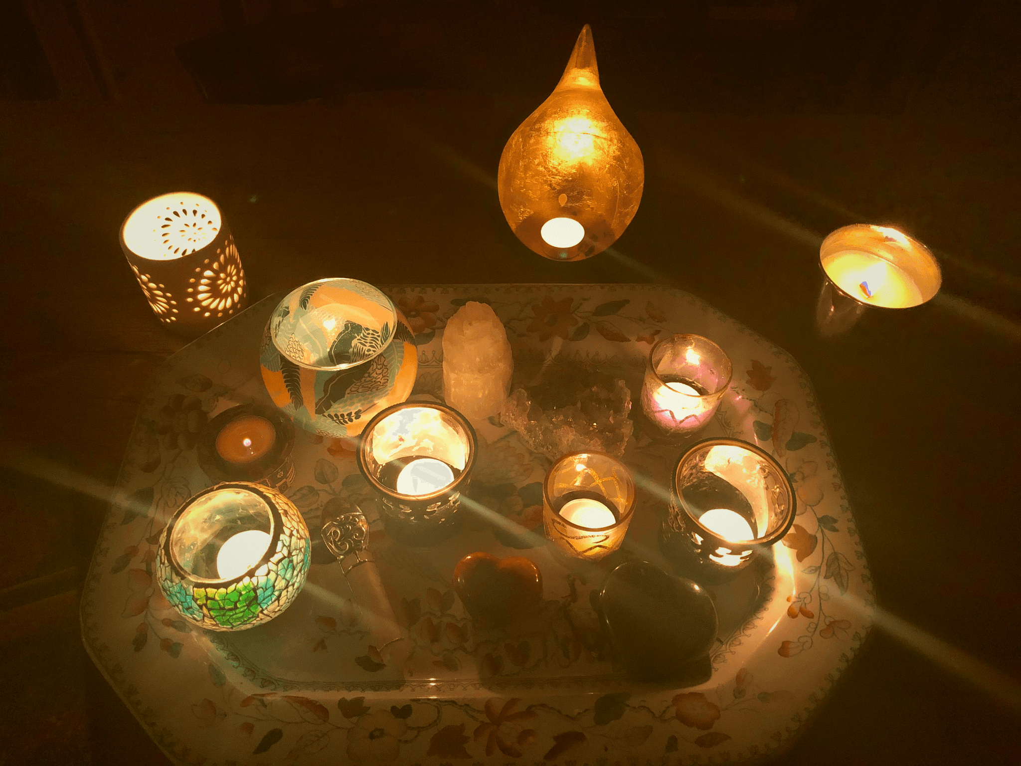 A serene and elegant spa space with wooden reclining chairs and white cushions. Golden sunlight filters through a cascading water feature, creating a peaceful atmosphere. Tropical plants and candles add to the relaxing ambiance.